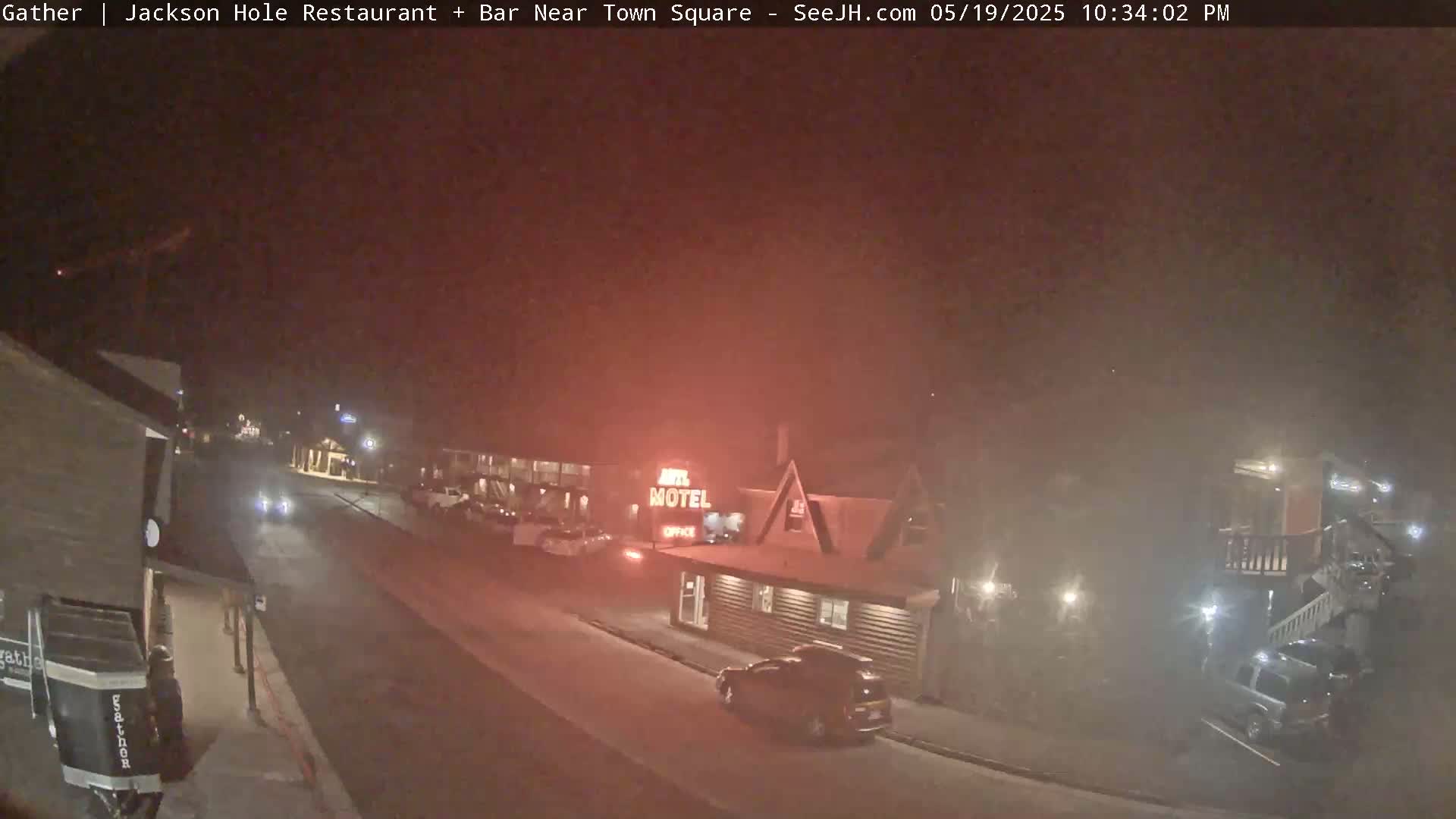 A nighttime street scene shows a motel and a few cars under hazy or foggy conditions.