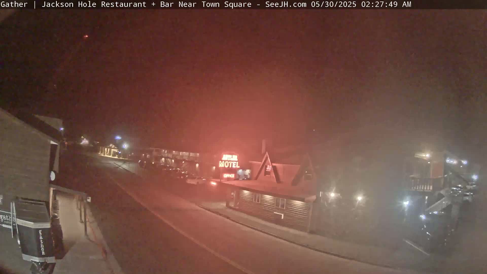 A nighttime street scene shows a motel and other buildings under hazy or foggy conditions.