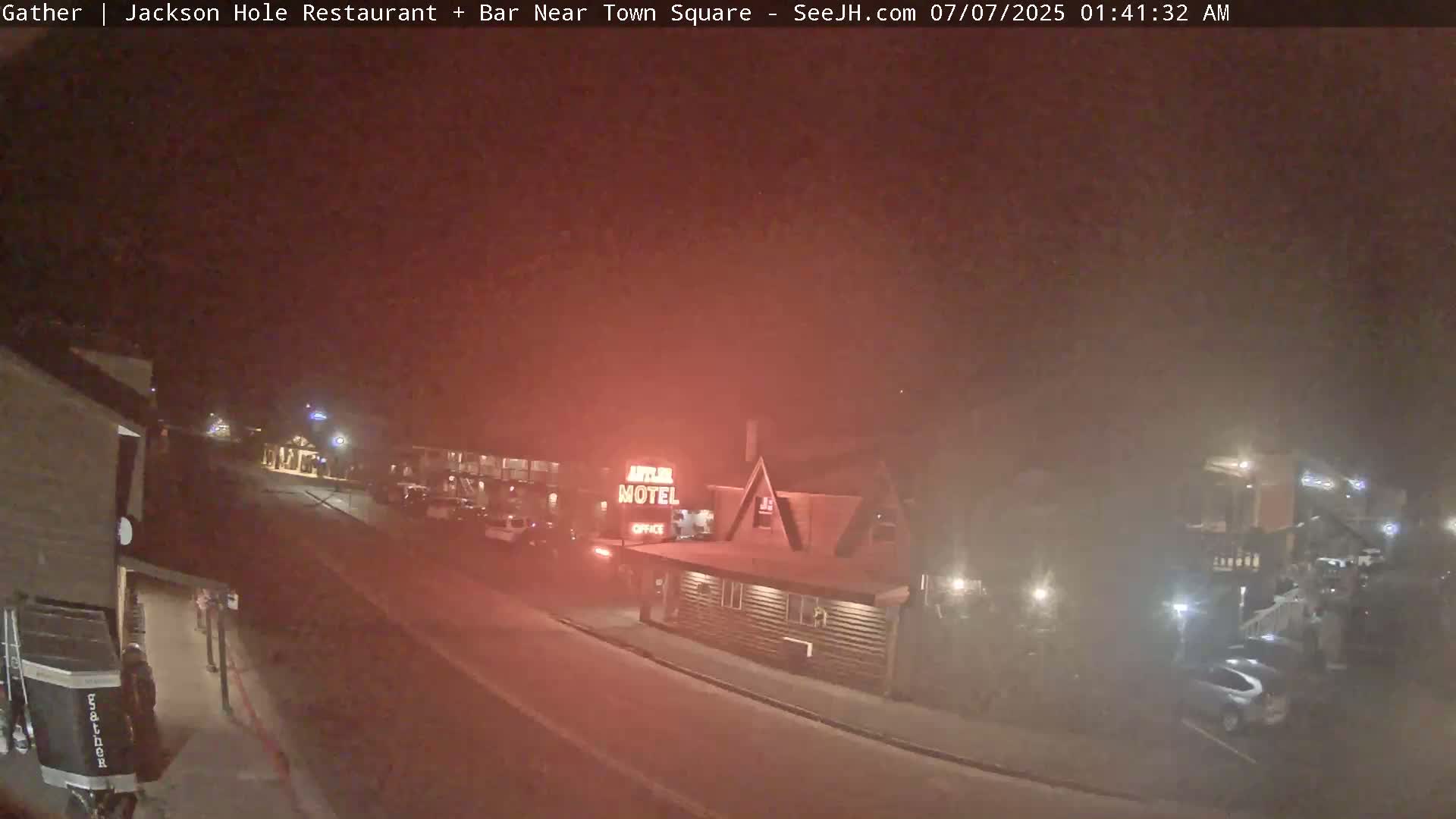 A nighttime street scene shows a motel and other buildings in hazy conditions.