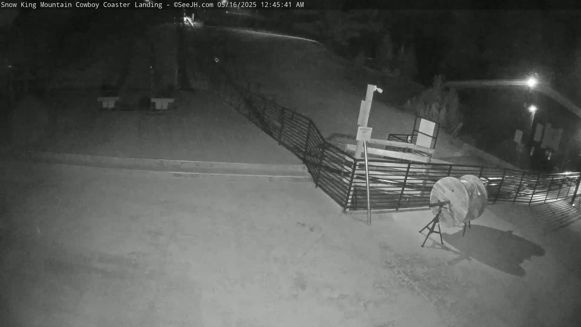A nighttime, snow-covered landing area with a metal fence and two cable spools is visible.