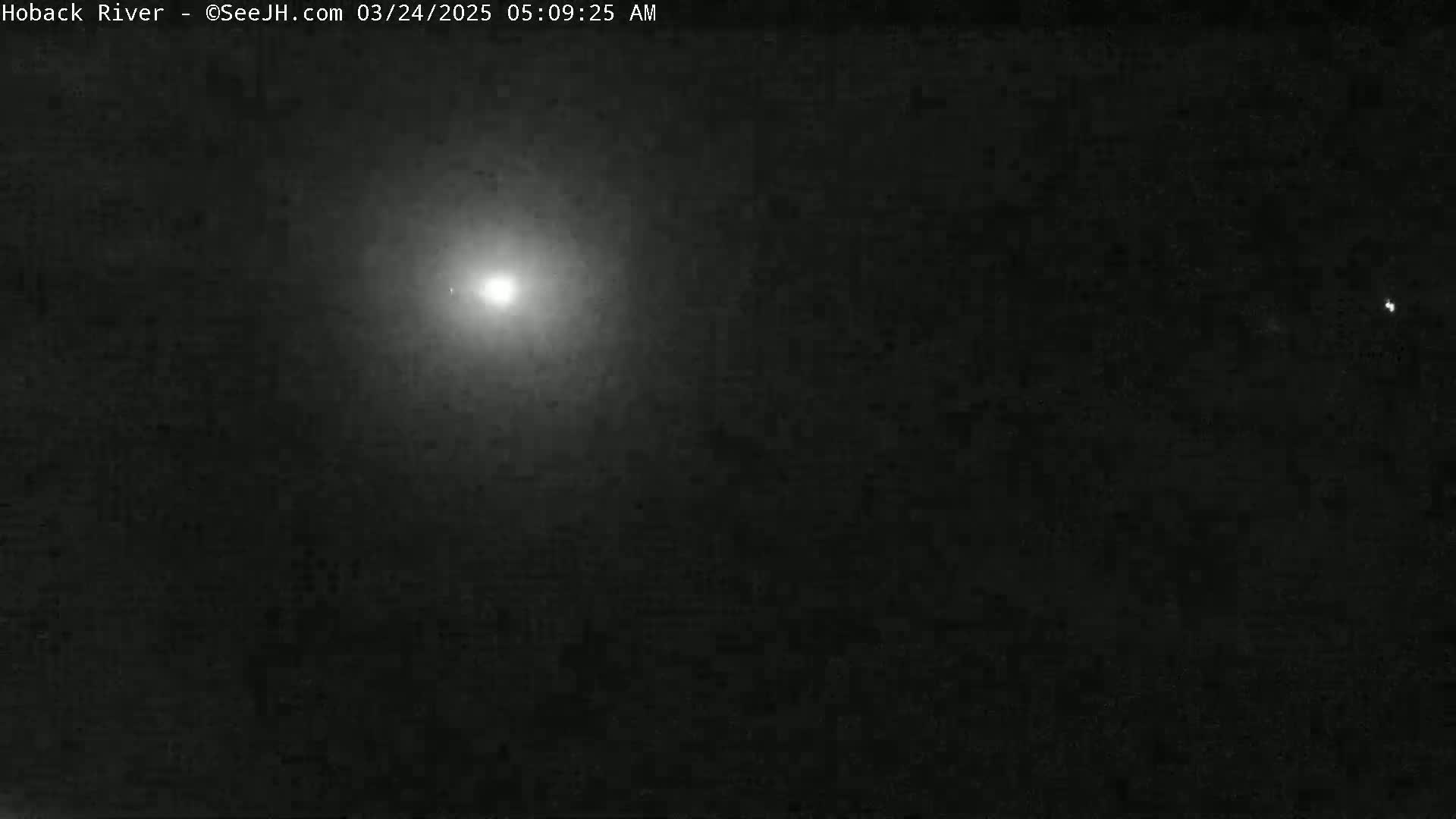 A bright light shines in a dark, nighttime sky.