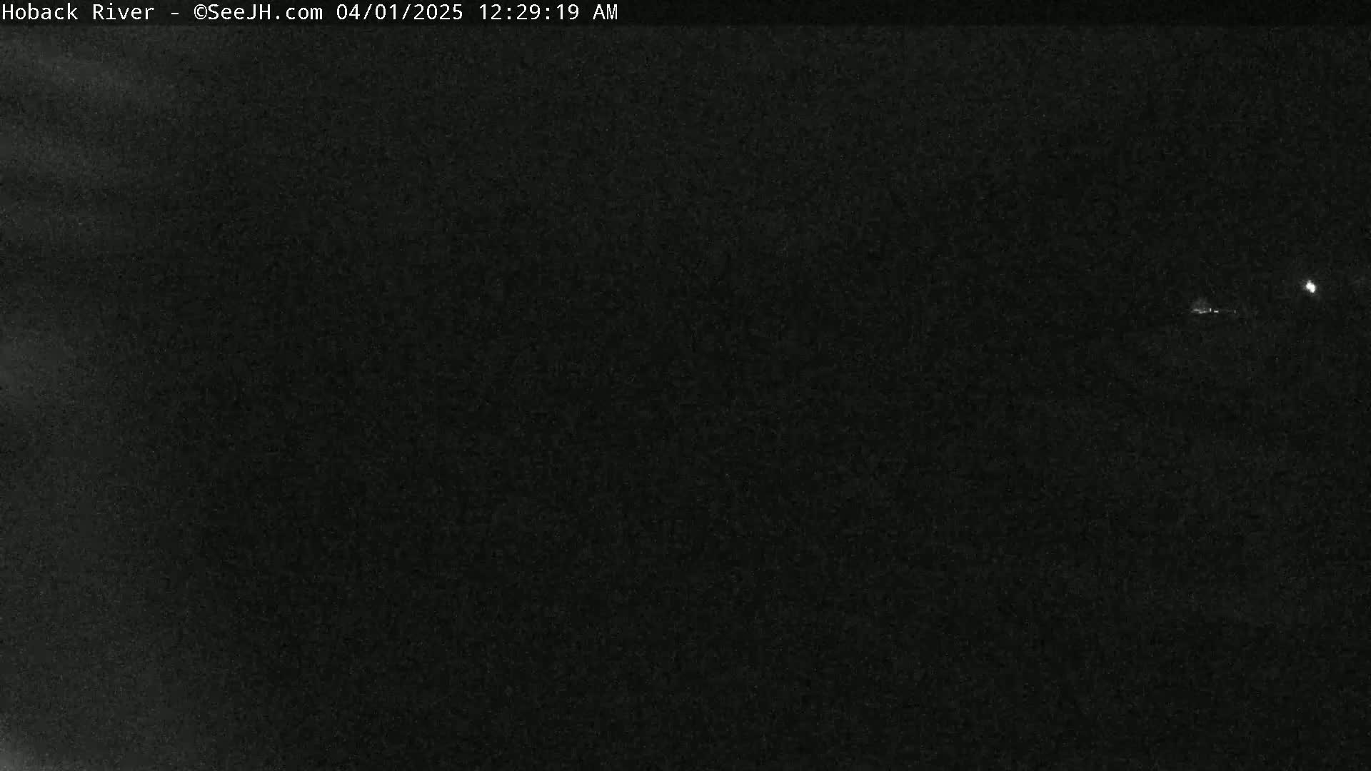A dark, nighttime image shows a faint light source in the distance.