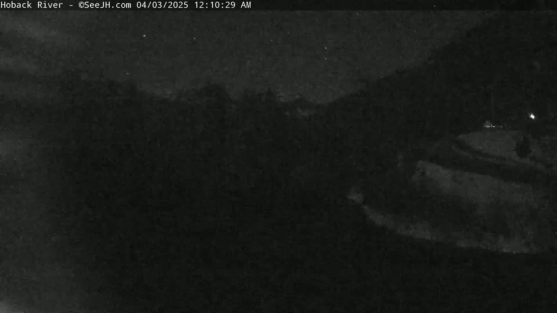 A dark, nighttime scene shows a mostly obscured landscape under a mostly clear sky.