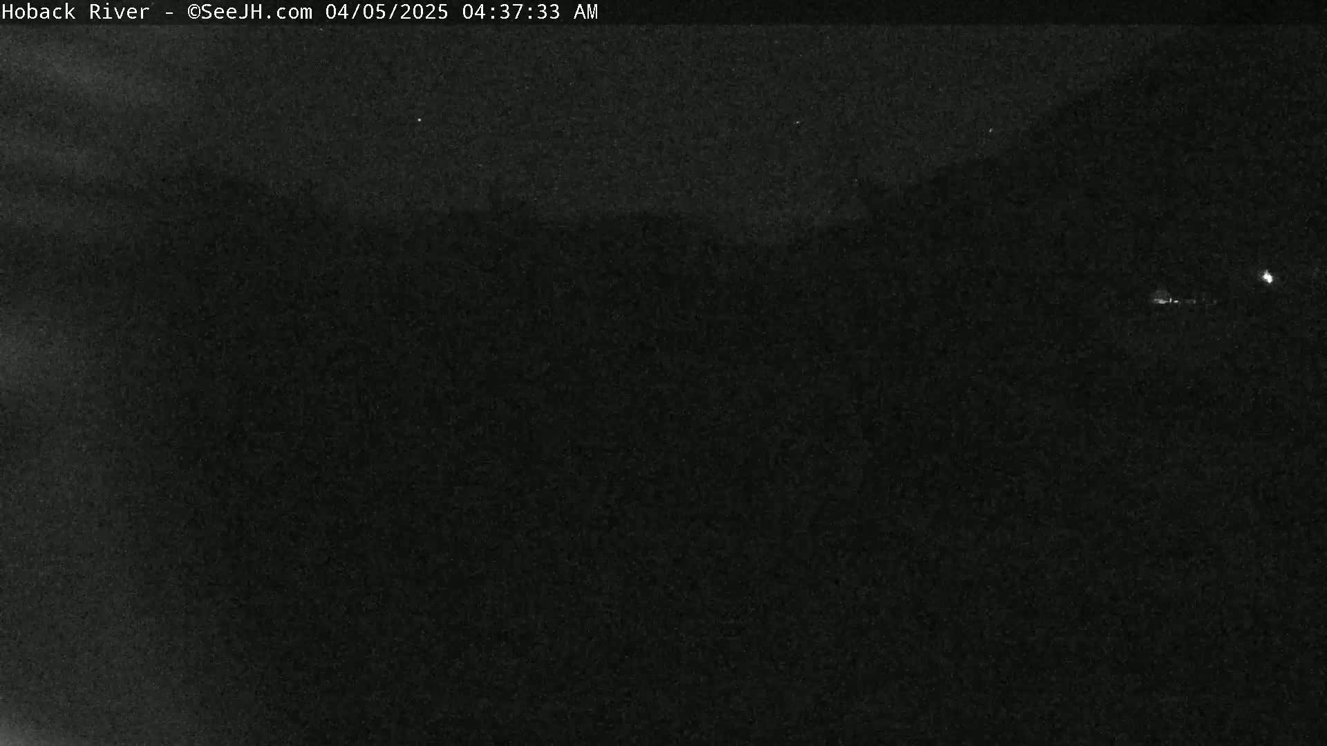 A dark, nighttime scene shows a mostly featureless landscape under a clear sky.