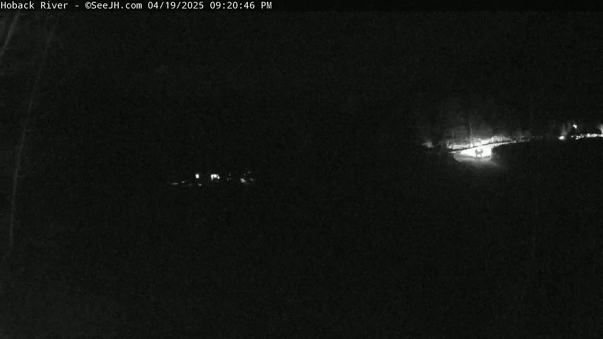 A nighttime, low-light image shows a dark road with faint vehicle headlights in the distance.