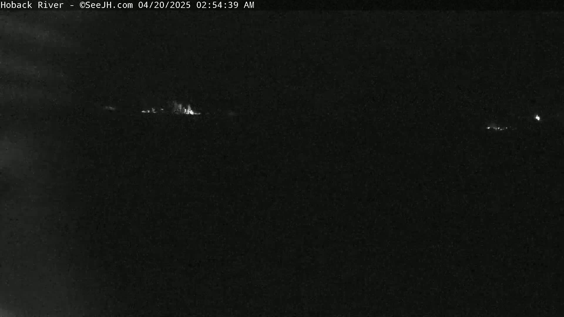 A nighttime long shot shows a few faint lights in the distance under a dark sky.