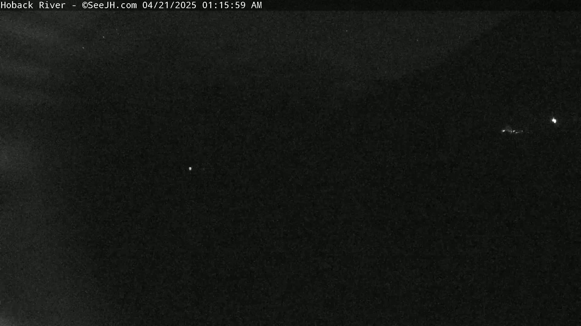 A dark, nighttime scene shows a few faint lights in the distance under a mostly clear sky.