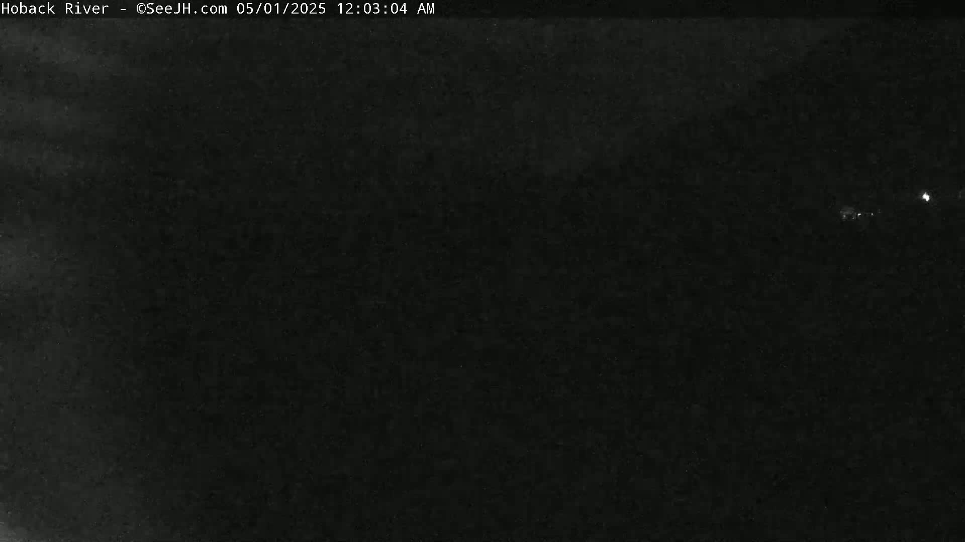 A very dark, nighttime image shows a few faint lights in the distance.