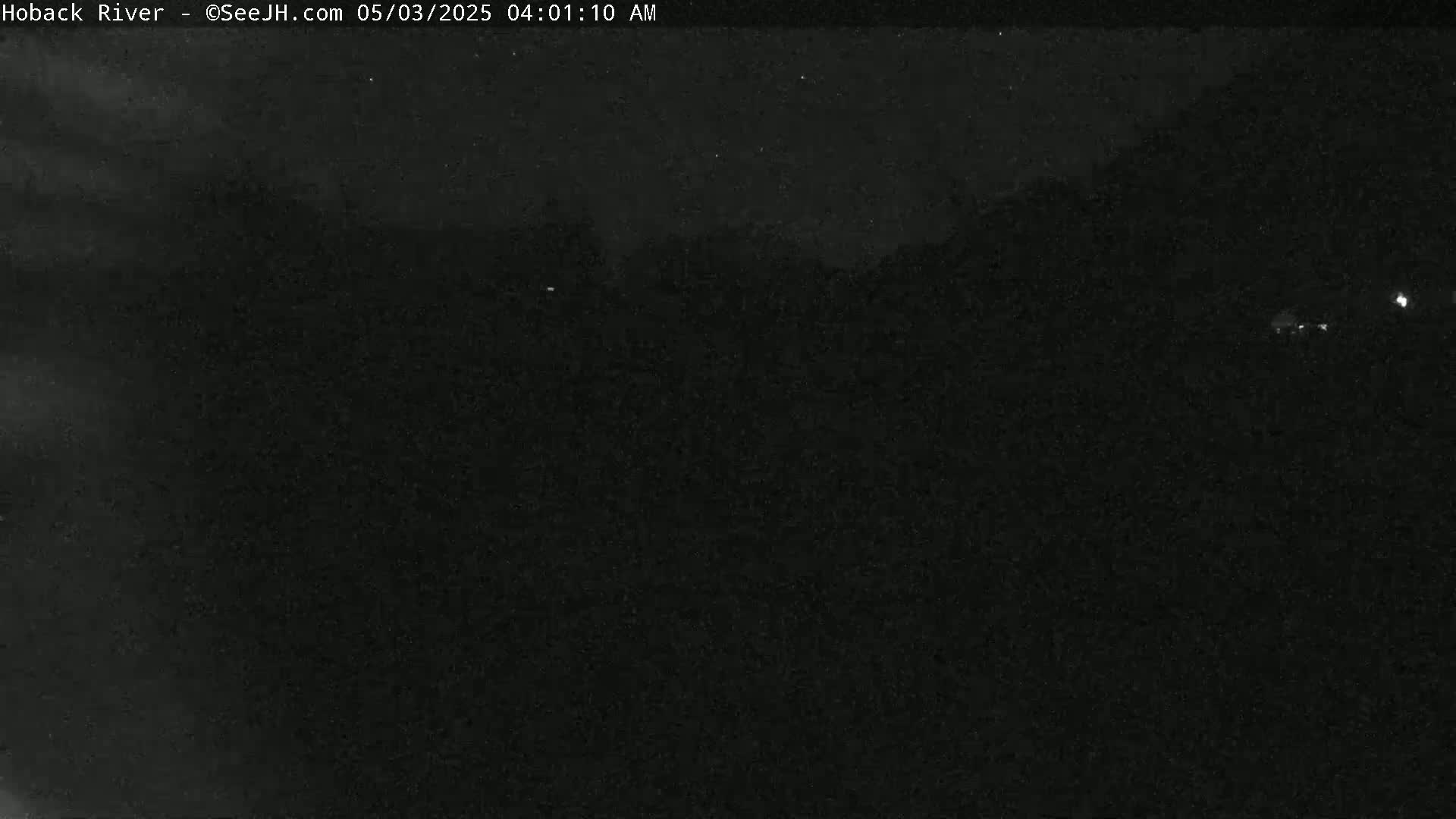 A nighttime, low-light image shows a dark, indistinct landscape.