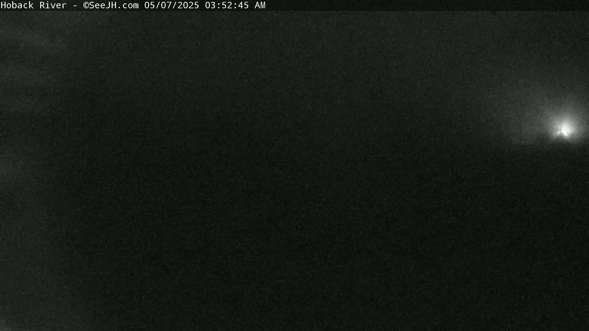 A mostly dark image shows a bright light source in the upper right corner, suggesting nighttime conditions.