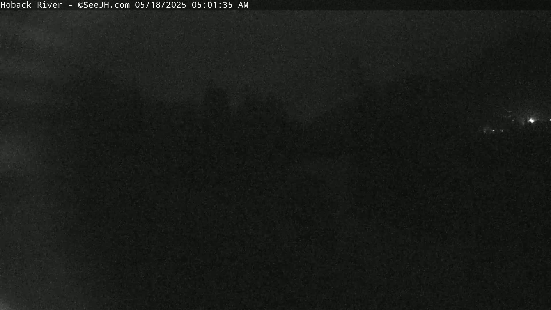 A dark, nighttime scene shows a mostly featureless landscape under a cloudy sky.