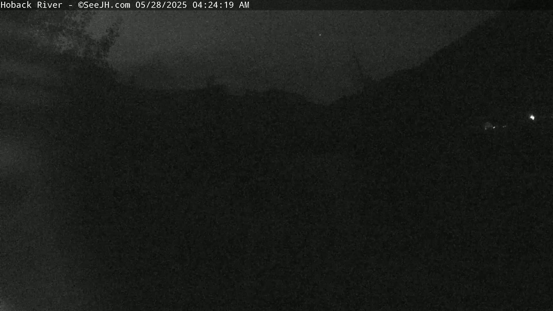 A nighttime, dark, and blurry outdoor image shows a landscape under a mostly clear sky.