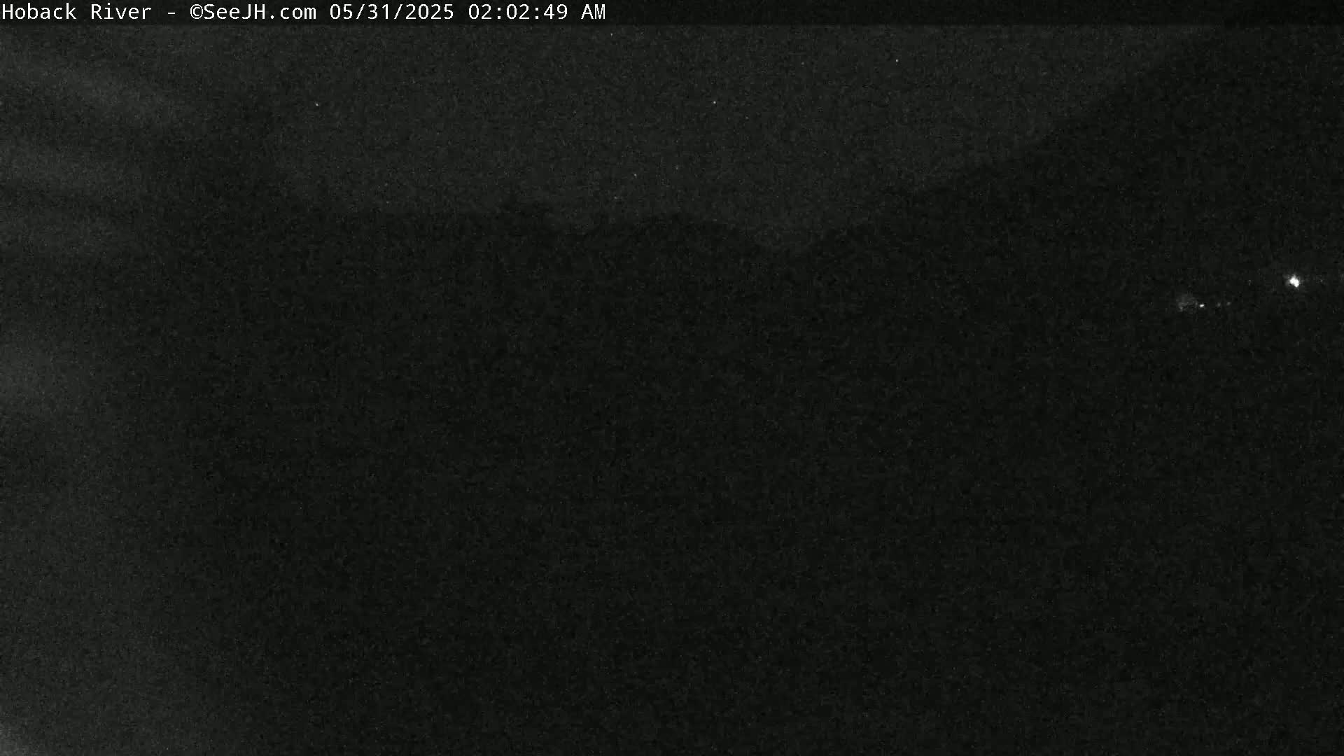 A nighttime, dark, grainy image shows a largely featureless landscape under a clear sky.