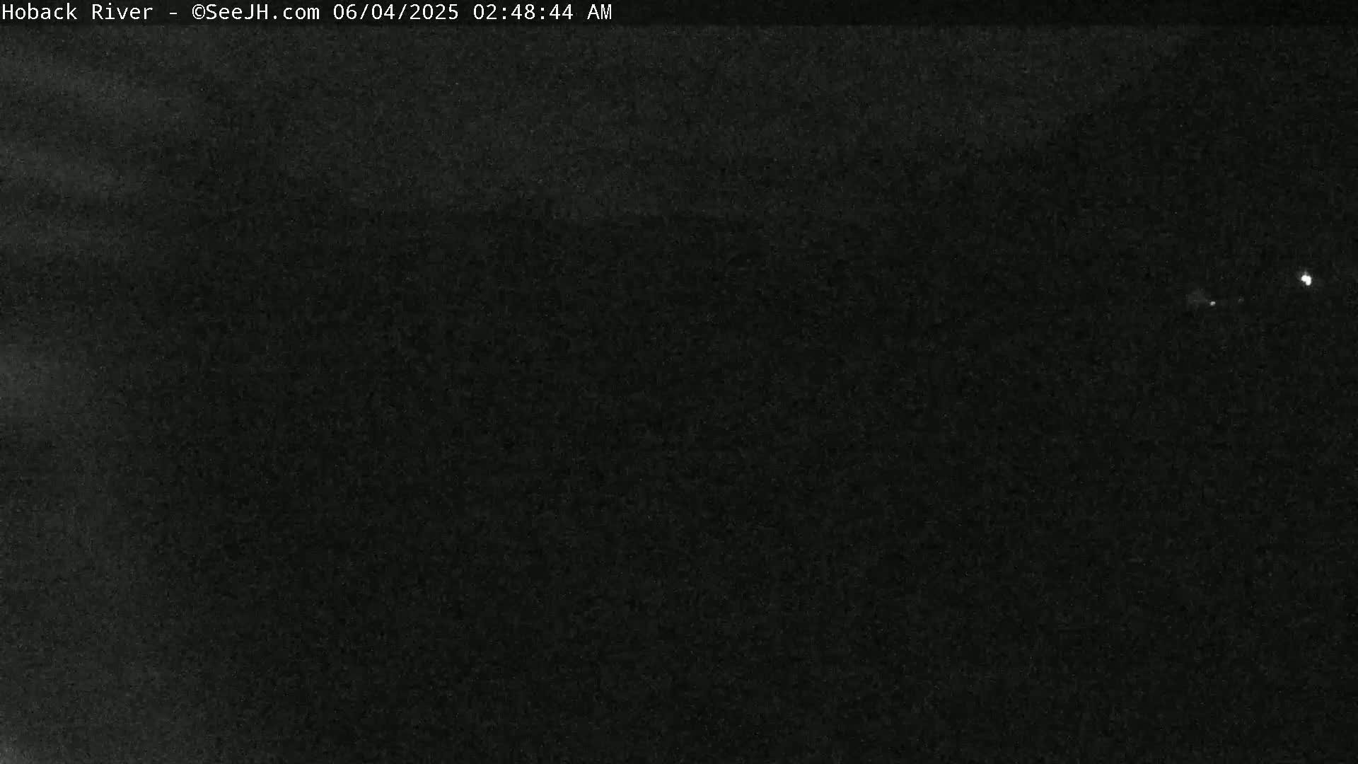A dark, nighttime image shows a mostly featureless, black sky with a few faint, distant lights.