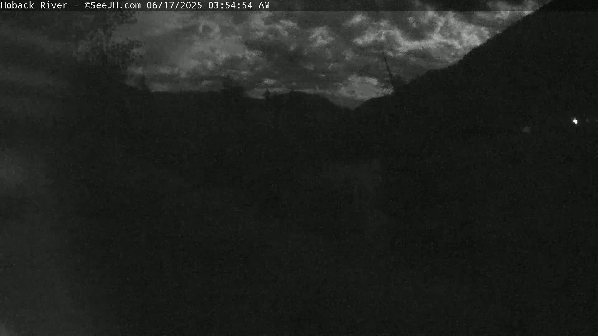 A dark, nighttime scene shows a cloudy sky over a silhouetted landscape.