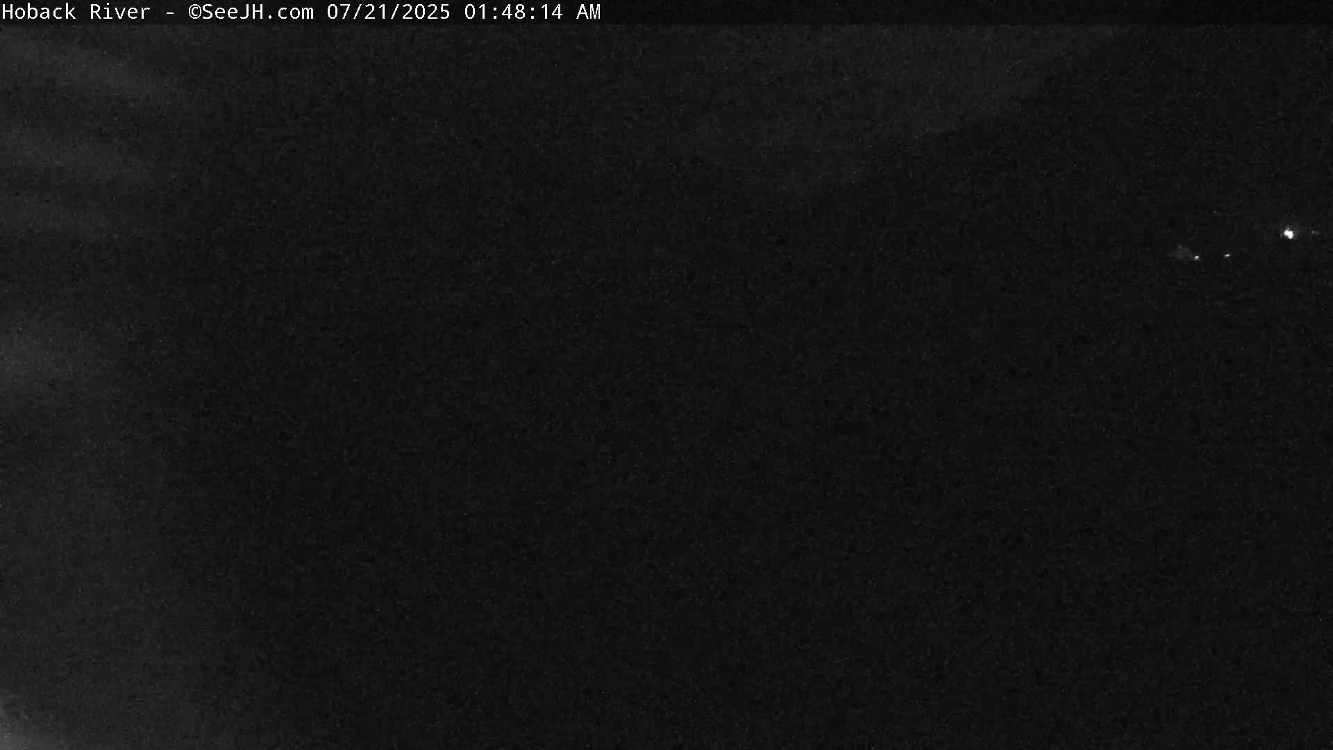 A nighttime, dark image shows a mostly clear sky with a few faint lights in the distance.