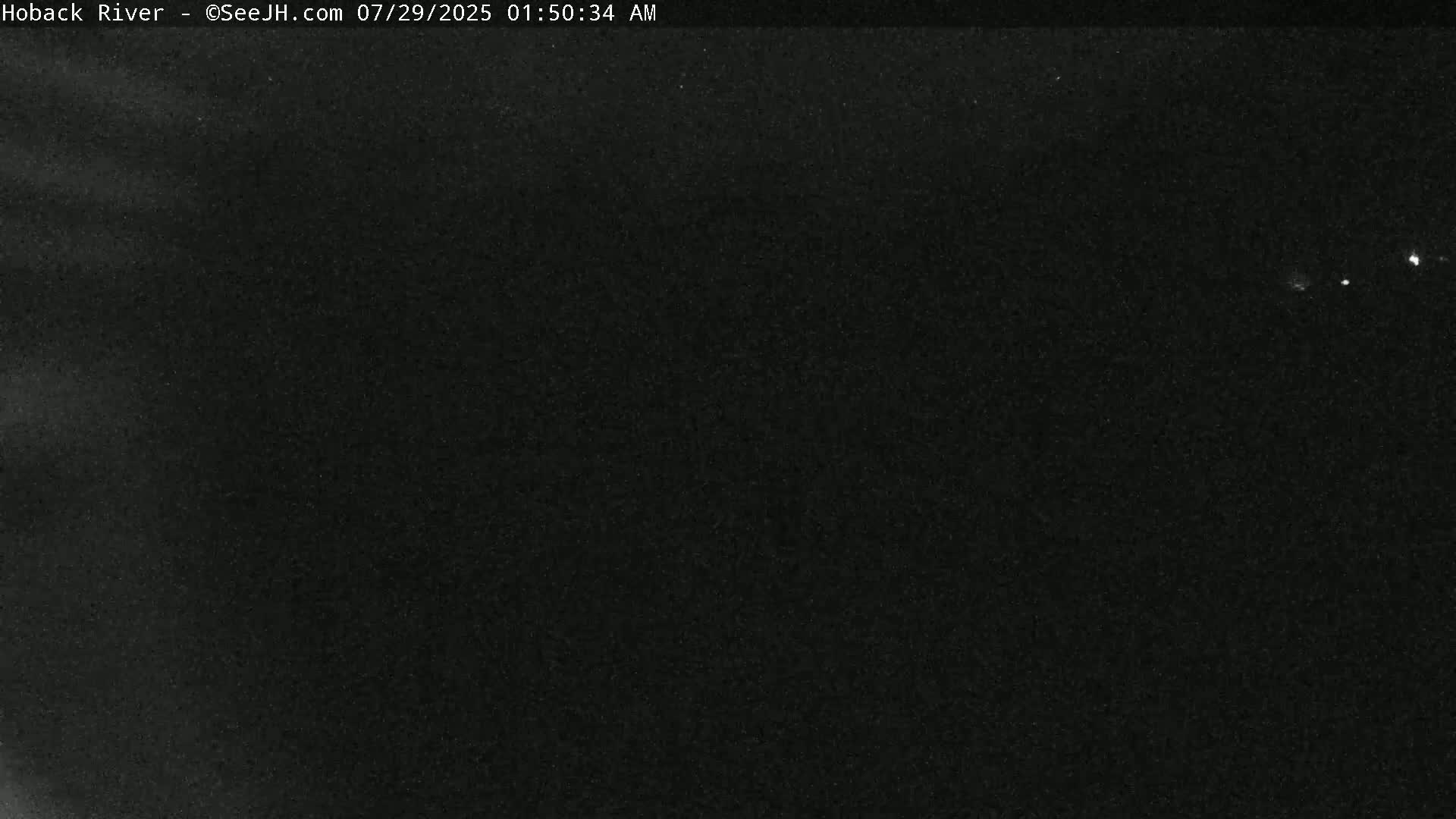 A dark, nighttime image shows a few faint lights in the distance against a mostly black sky.
