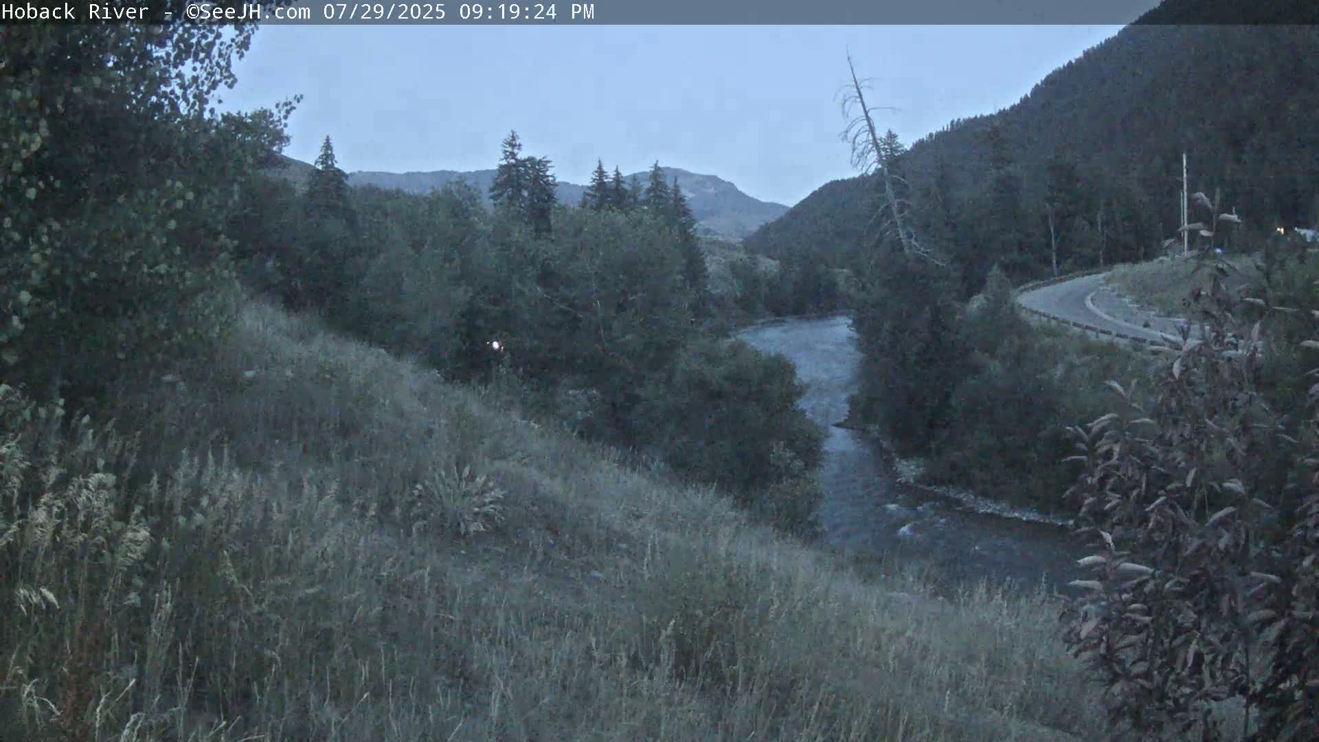 A dark, nighttime image shows a few faint lights in the distance against a mostly black sky.