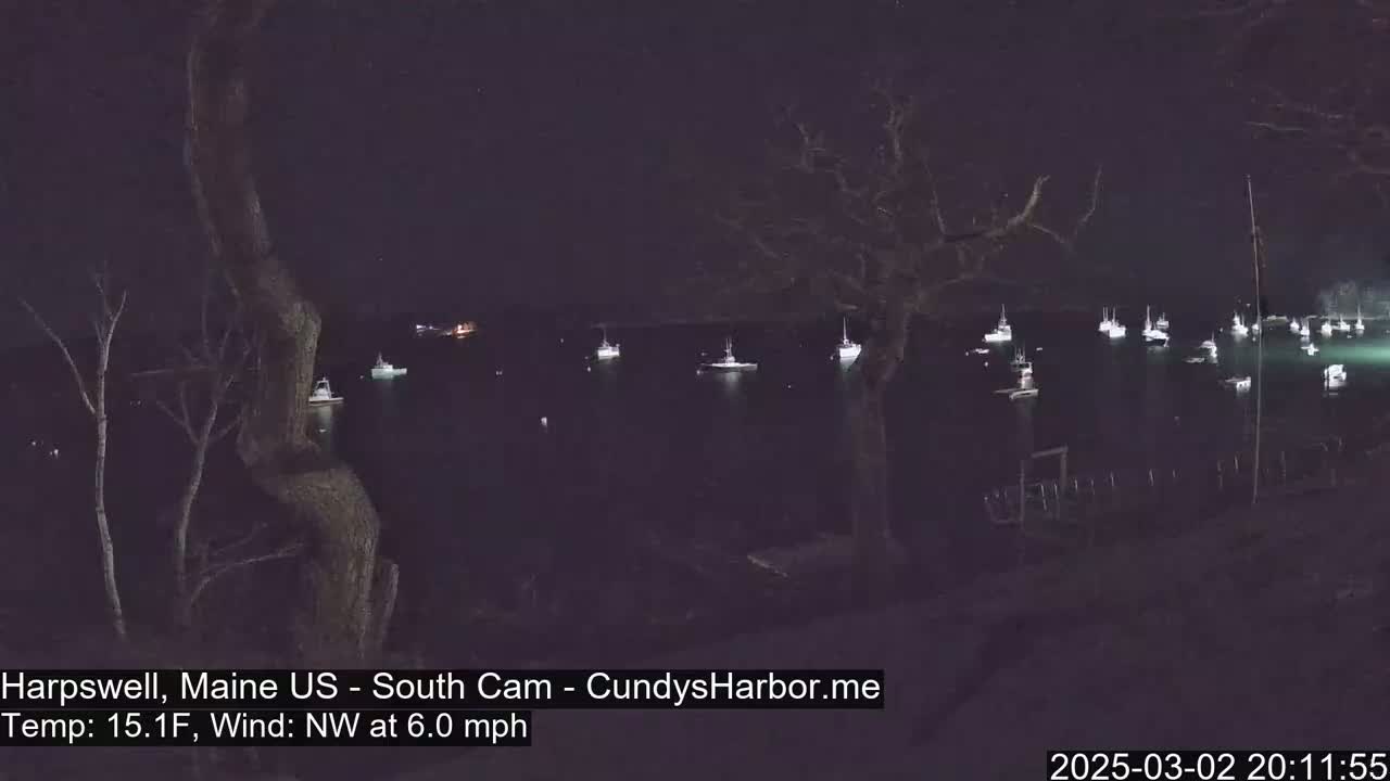 A nighttime view of numerous boats in a harbor, with a northwest wind at 6.0 mph and a temperature of 15.1°F.