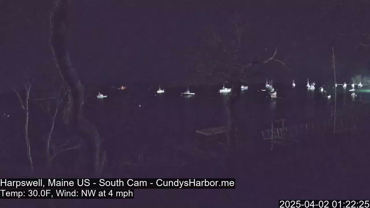 Several boats are moored in a dark harbor at night under a clear, starry sky with a northwest wind at 4 mph and a temperature of 30°F.