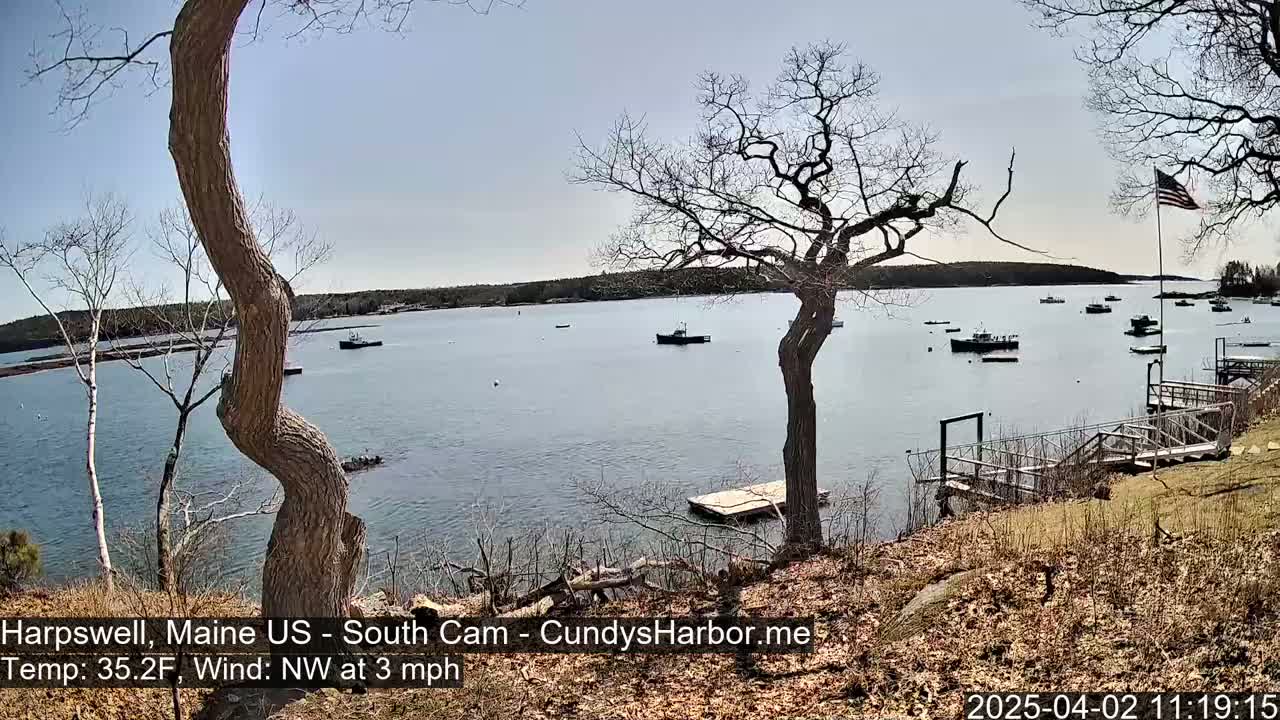 A calm body of water with several boats is seen from a high vantage point on a sunny day with a northwest wind of 3 mph and a temperature of 35.2°F.