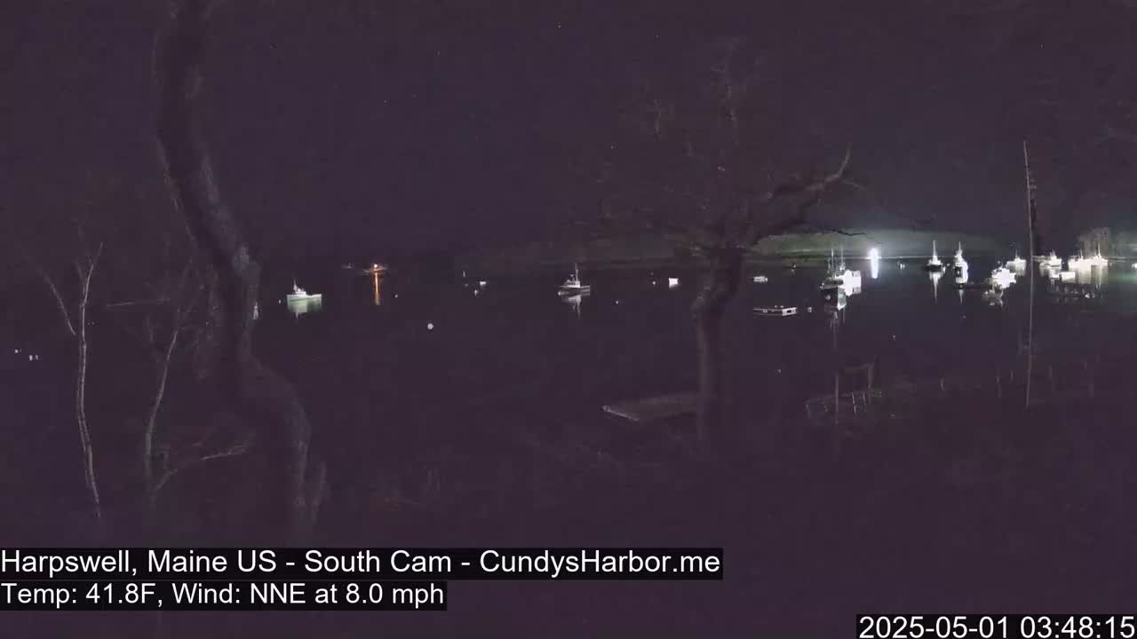 Several boats are moored in a dark harbor at night under a clear, starry sky, with a light north-northeast wind.