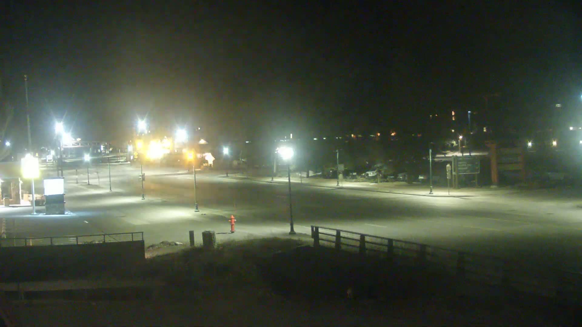 A mostly empty, brightly lit roadway at night under hazy conditions.