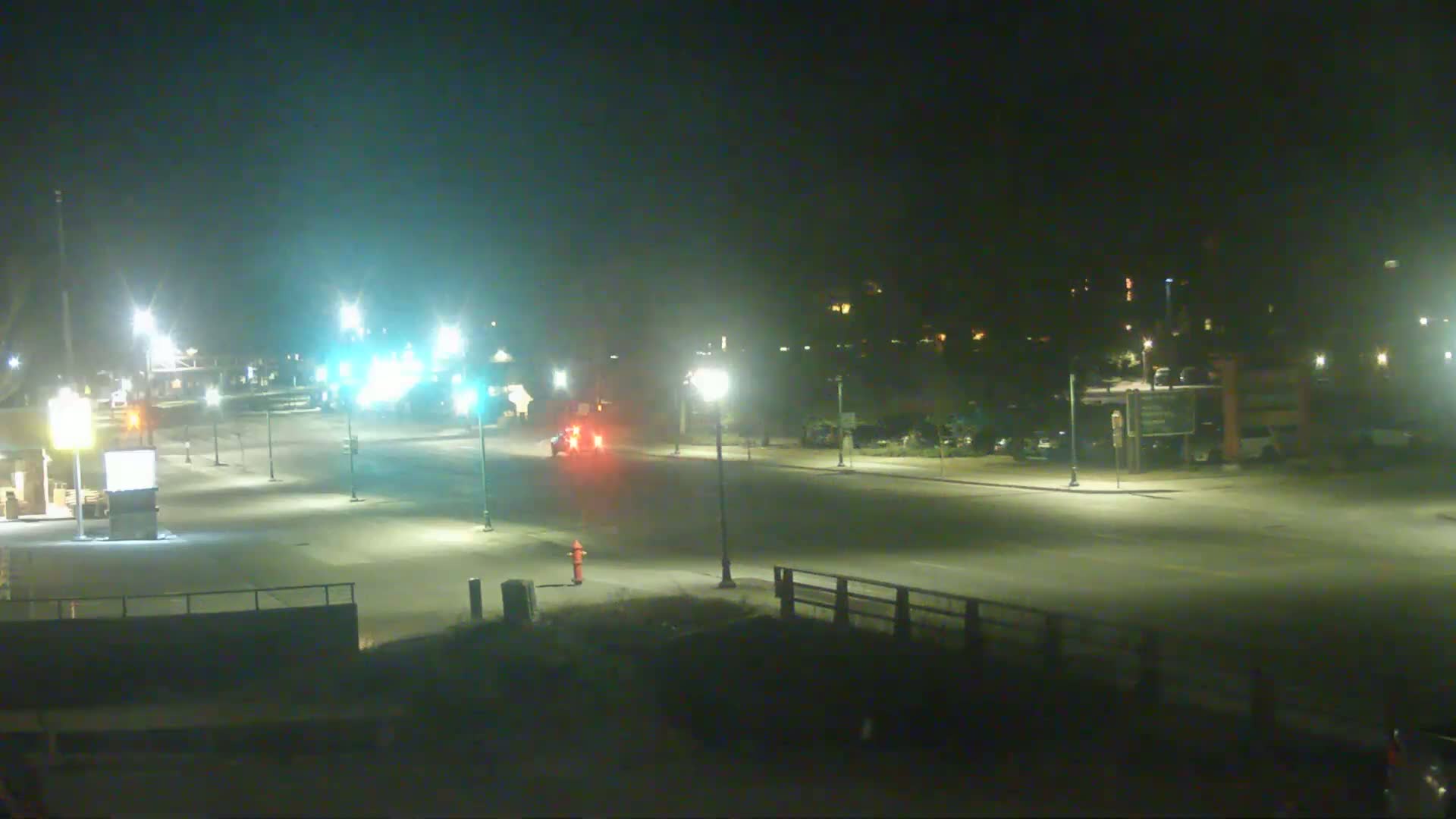 A mostly empty, well-lit street at night, with a few vehicles visible.