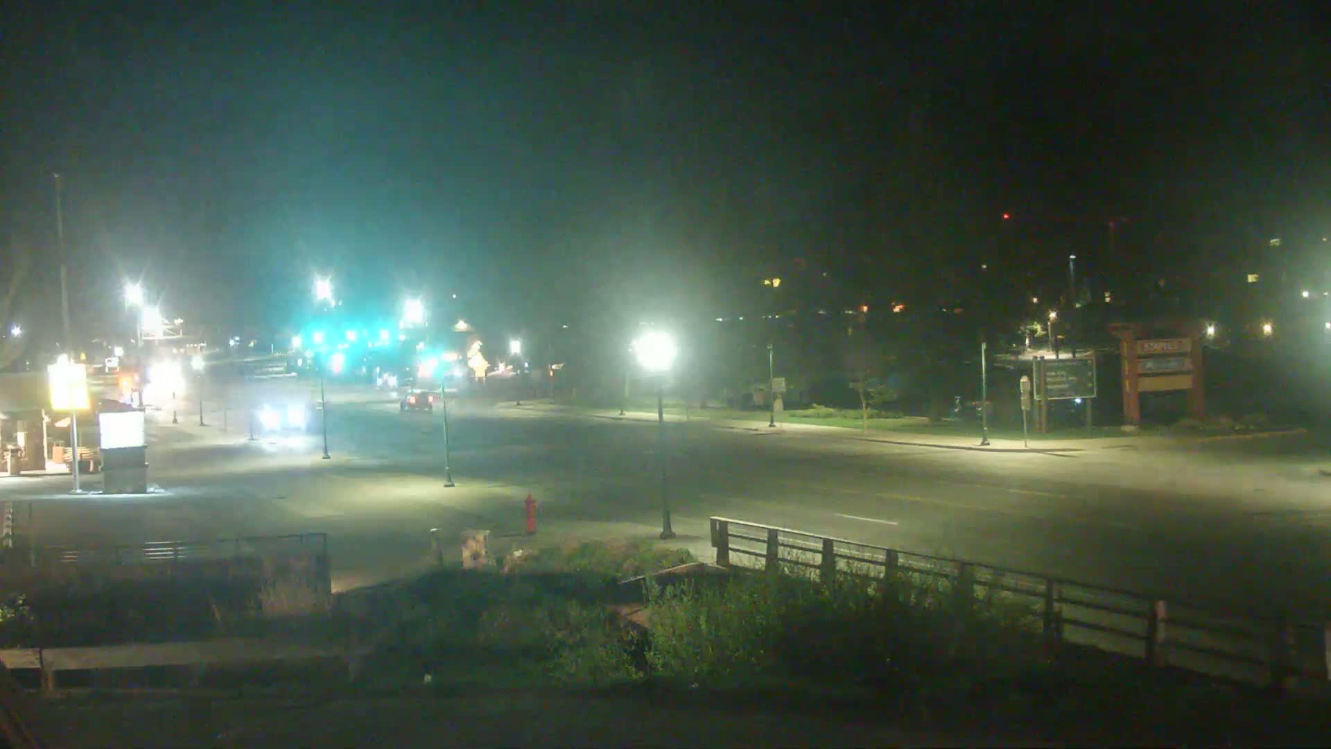 A nighttime view of a mostly empty road with several cars and streetlights, under clear skies.