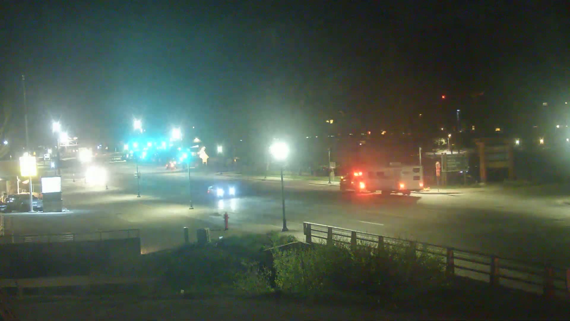 A nighttime street scene shows several vehicles at an intersection under illuminated streetlights.