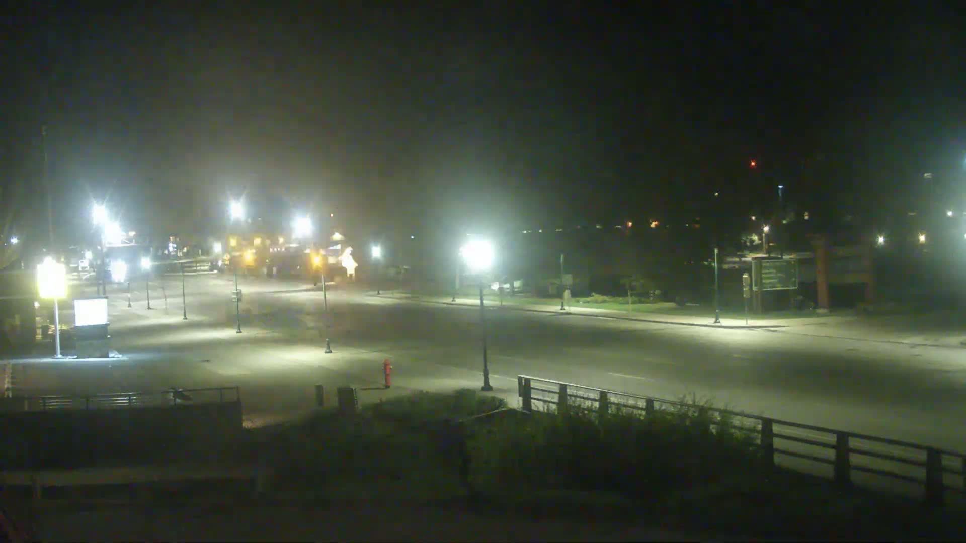 A mostly empty, brightly lit road at night is seen under hazy conditions.