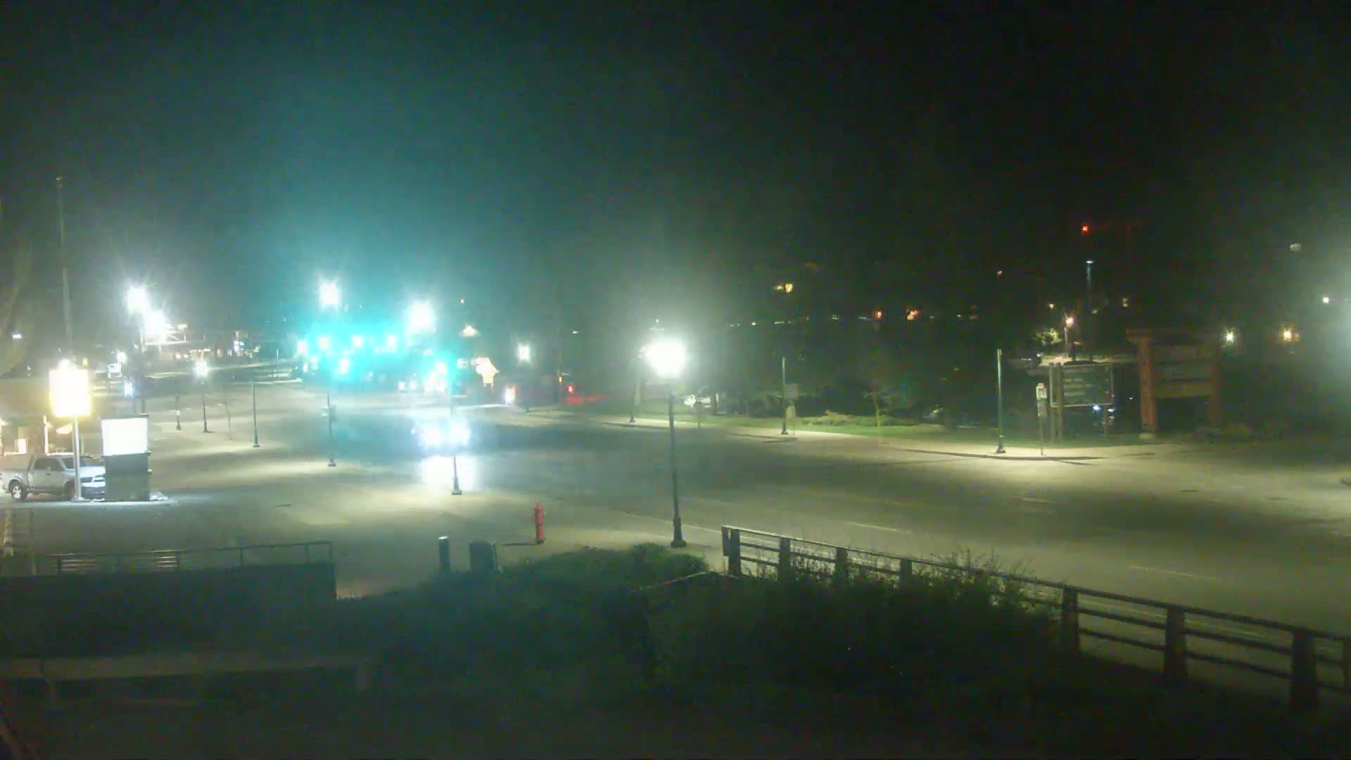 A mostly empty, well-lit roadway at night with a few vehicles visible.