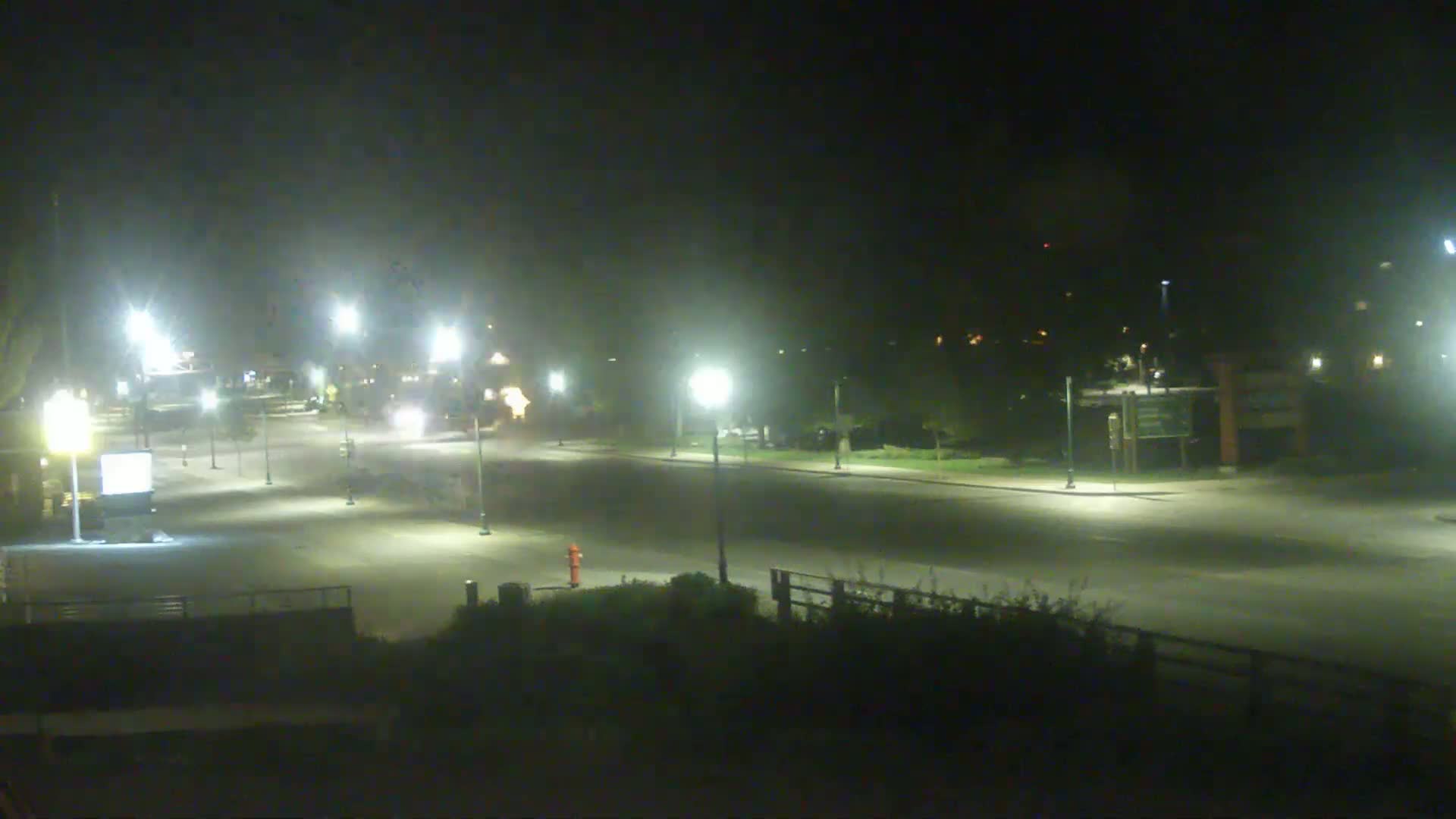 A mostly empty road at night, illuminated by streetlights, with a hazy atmosphere.