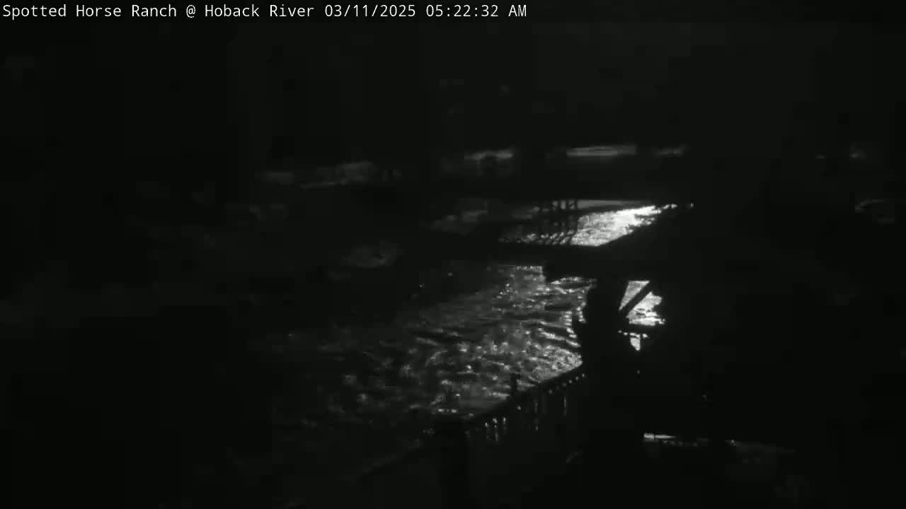 A nighttime view of a river flowing under a bridge, illuminated by moonlight.