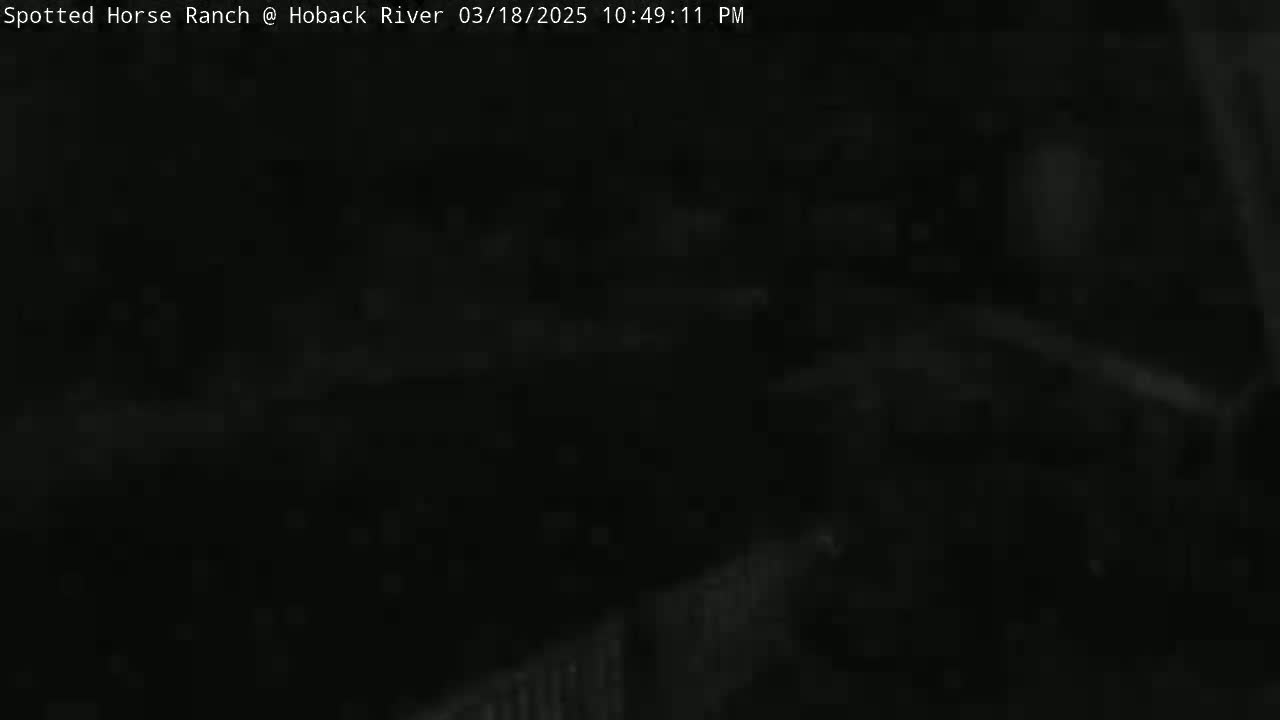A dark, nighttime outdoor scene shows a mostly obscured area, possibly a ranch, with a fence partially visible in the lower right corner.