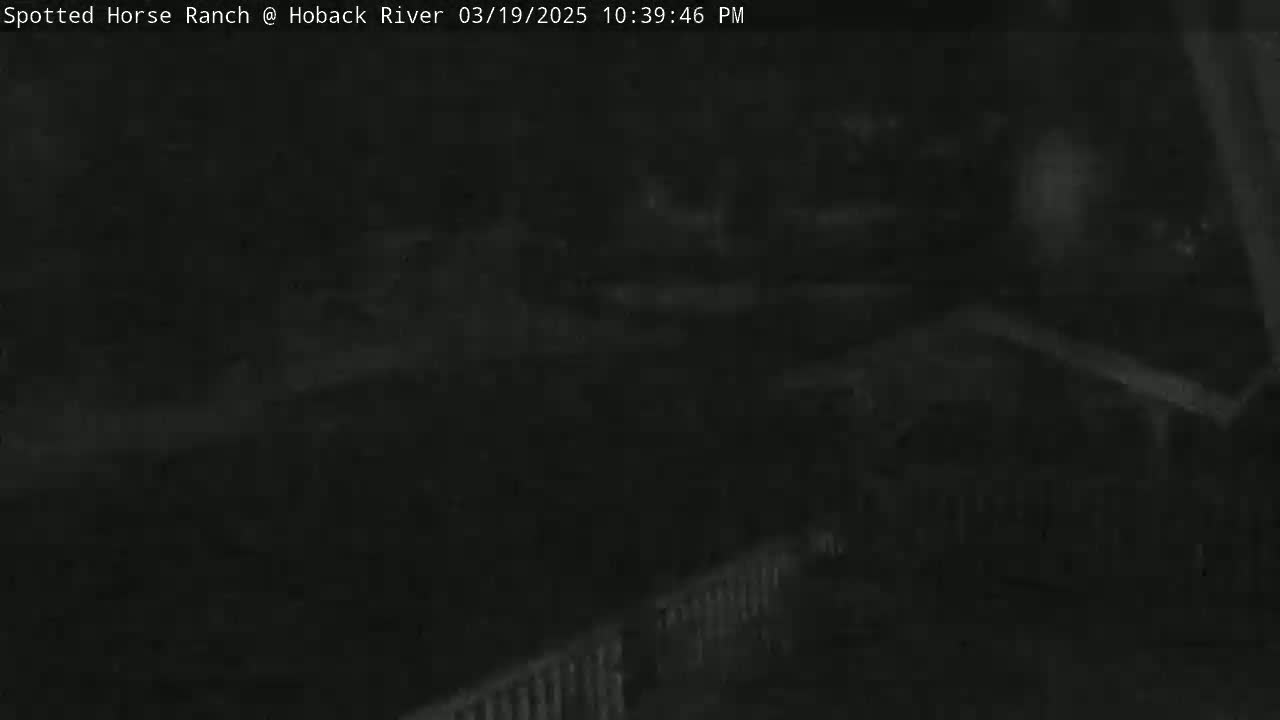A dark, nighttime image shows a blurry view of a structure and what appears to be a fence.