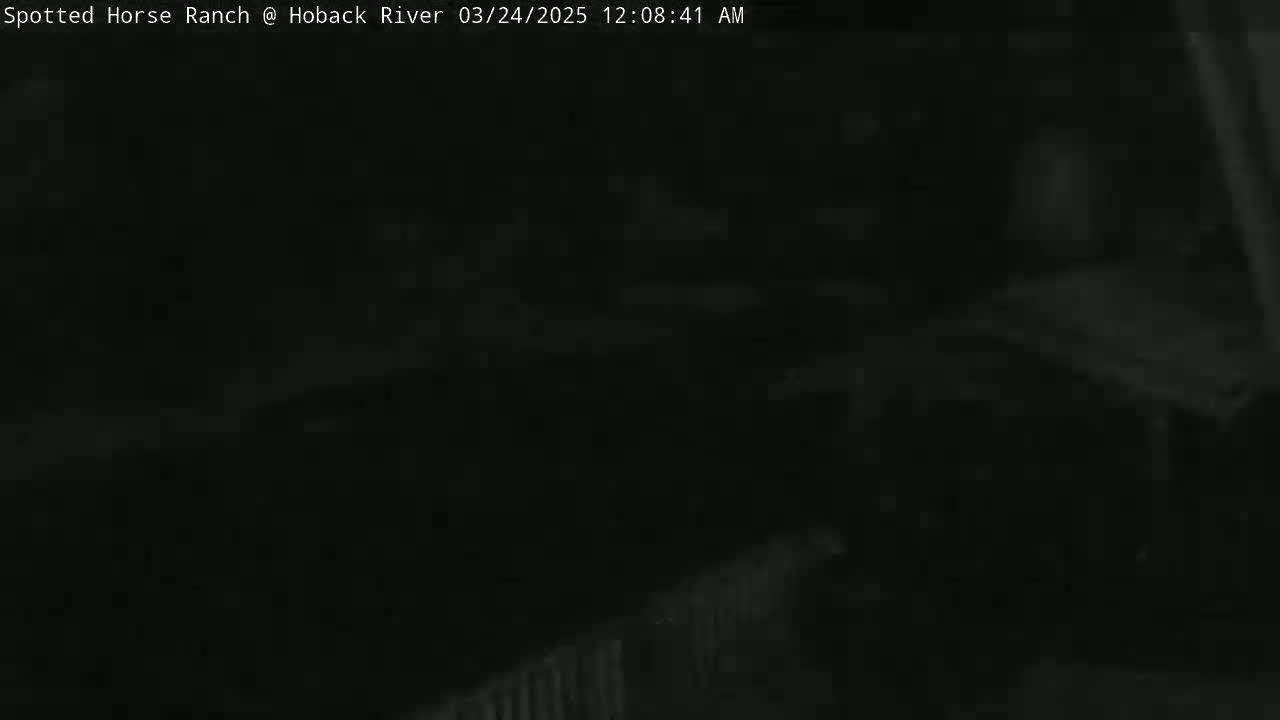 A very dark, nighttime image shows an indistinct outdoor scene with a low-light fence visible in the bottom right corner.