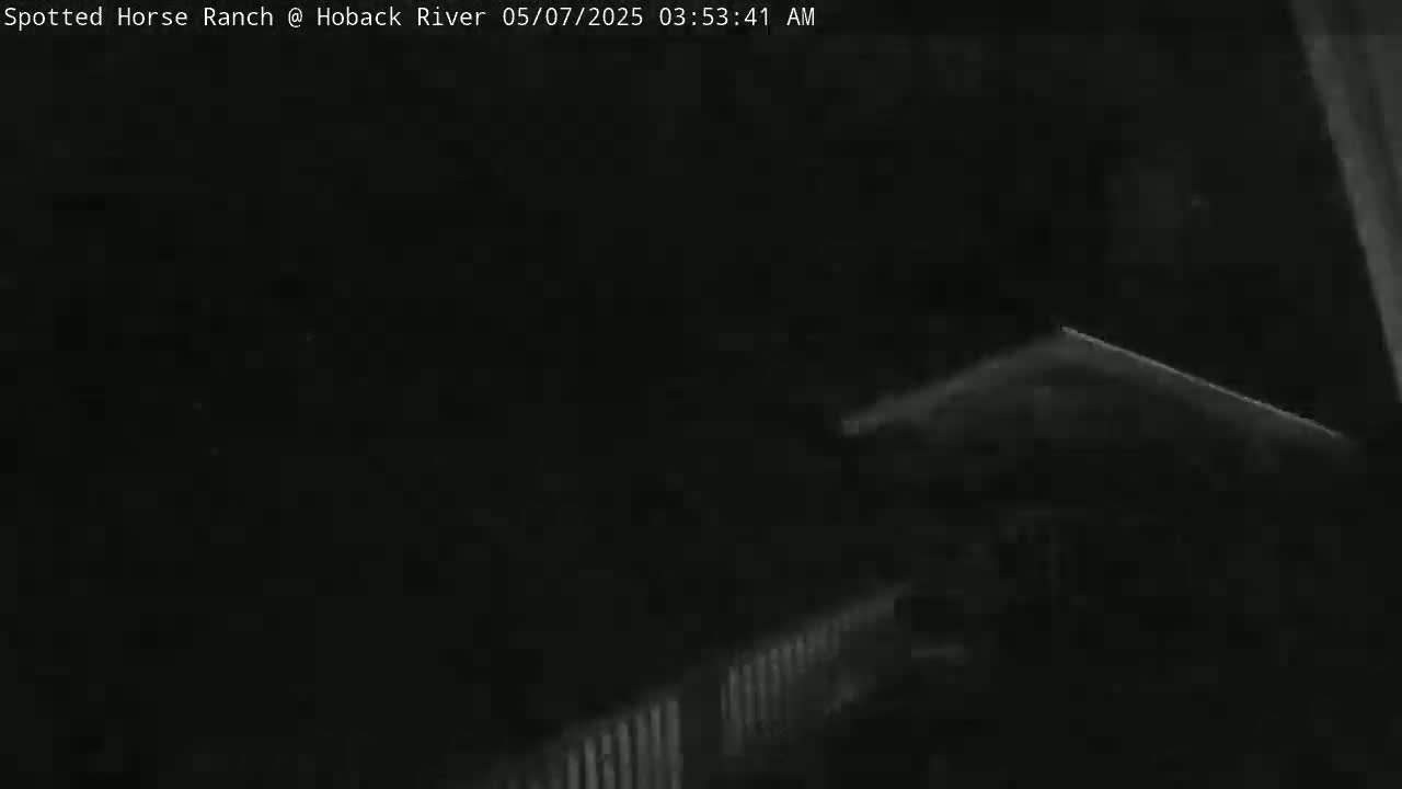 A low-light, nighttime image shows a dark structure with a fence-like feature in the bottom right corner.