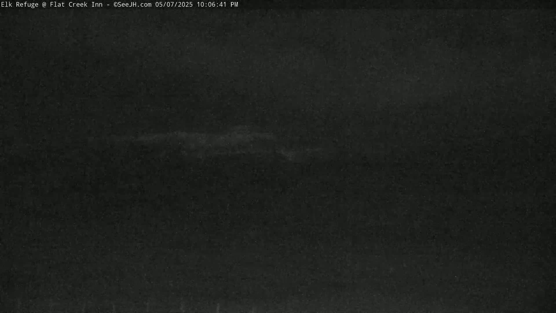 A dark, possibly nighttime, outdoor scene shows a faint, light horizontal streak across a mostly black sky.