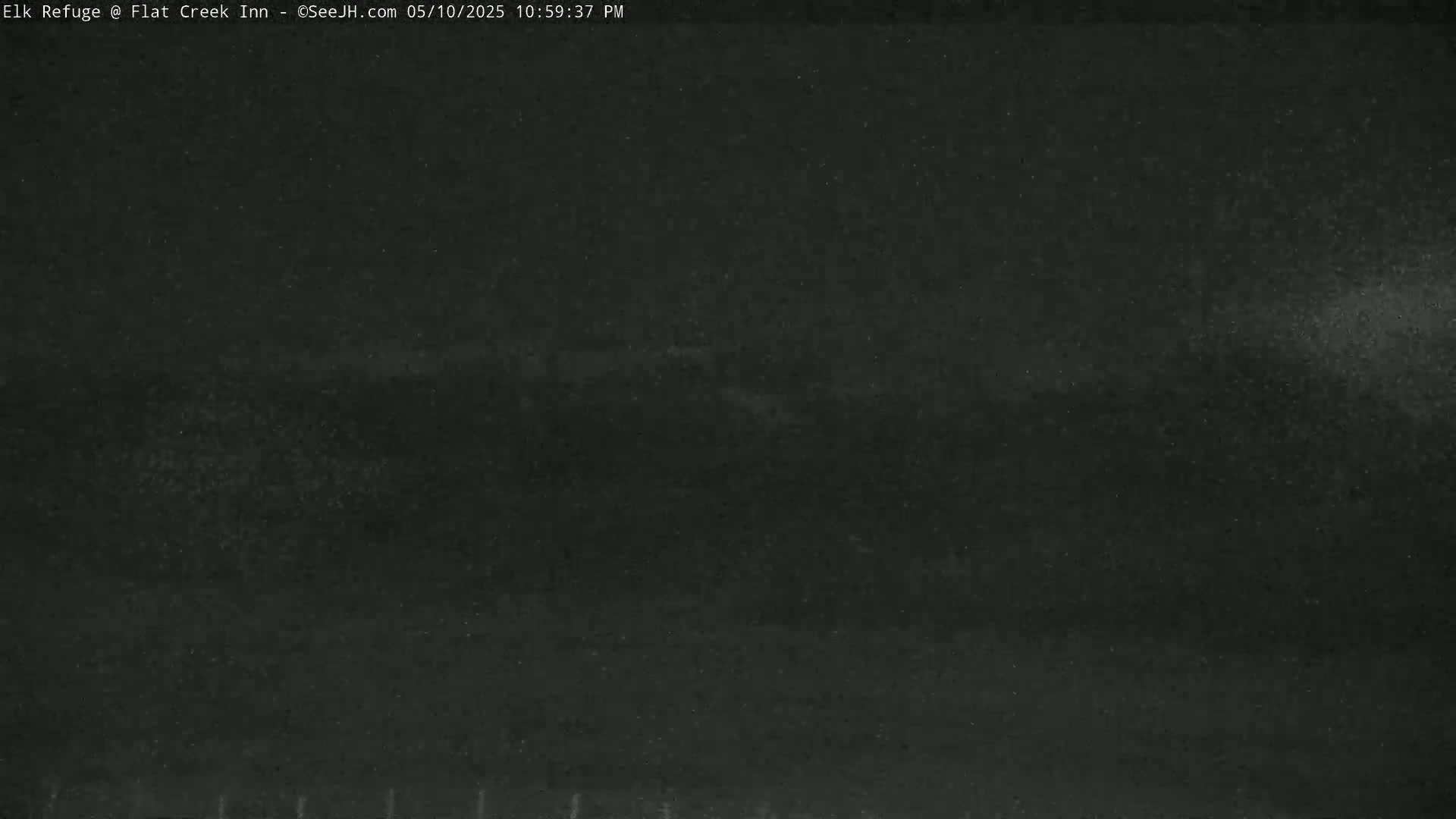 A dark, nighttime outdoor scene shows a mostly clear sky with a faint, hazy band near the horizon.