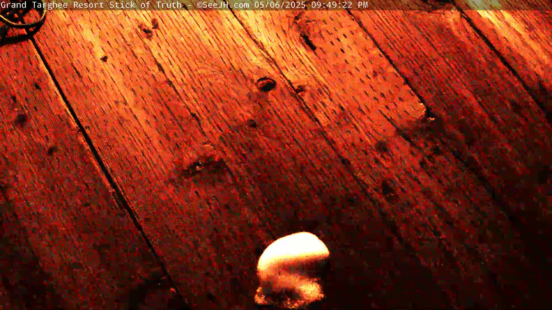 A partially visible, light-colored object rests on a dark reddish-brown wooden surface.