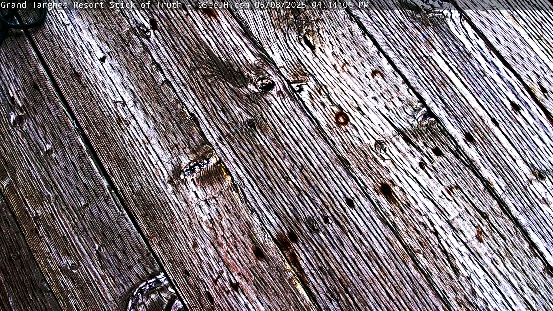 A close-up view shows weathered gray and brown wooden planks angled diagonally across the frame.