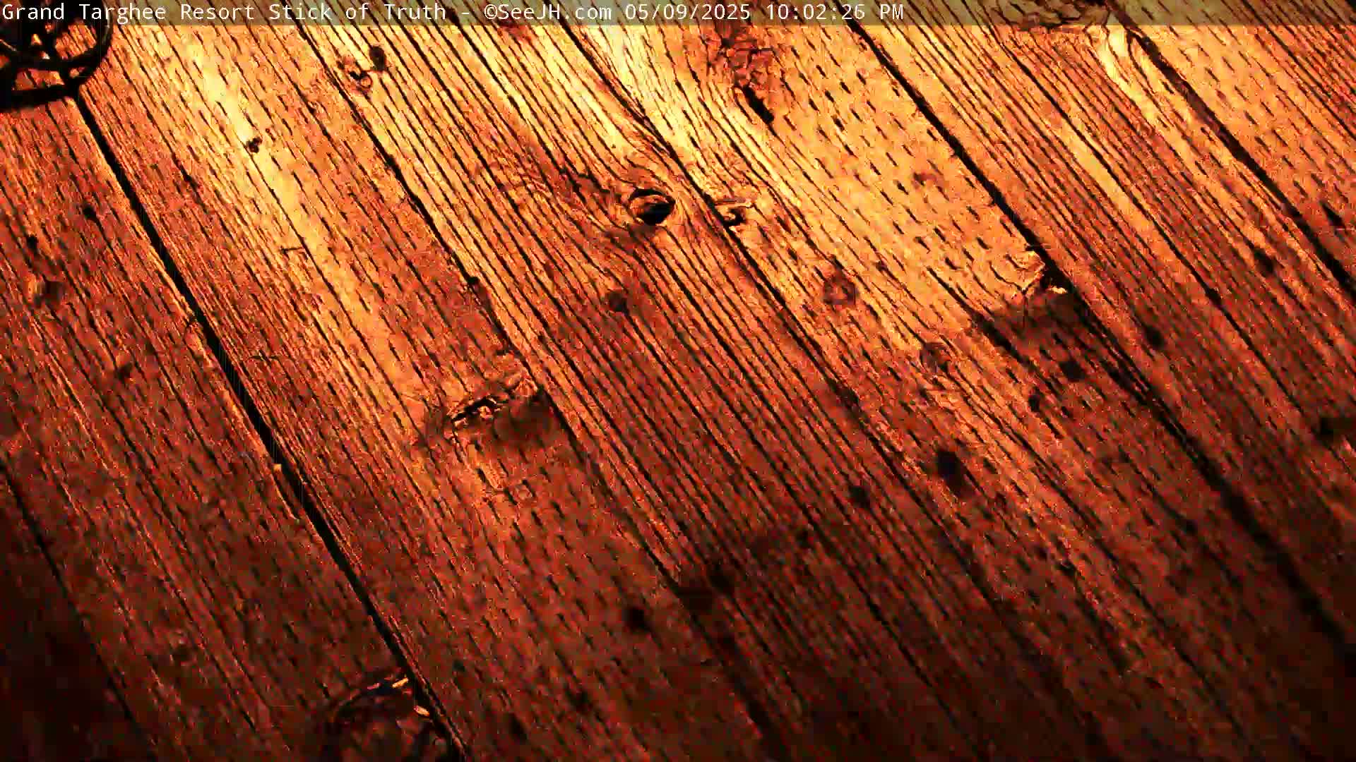 A close-up view shows a diagonal pattern of dark reddish-brown wooden planks.