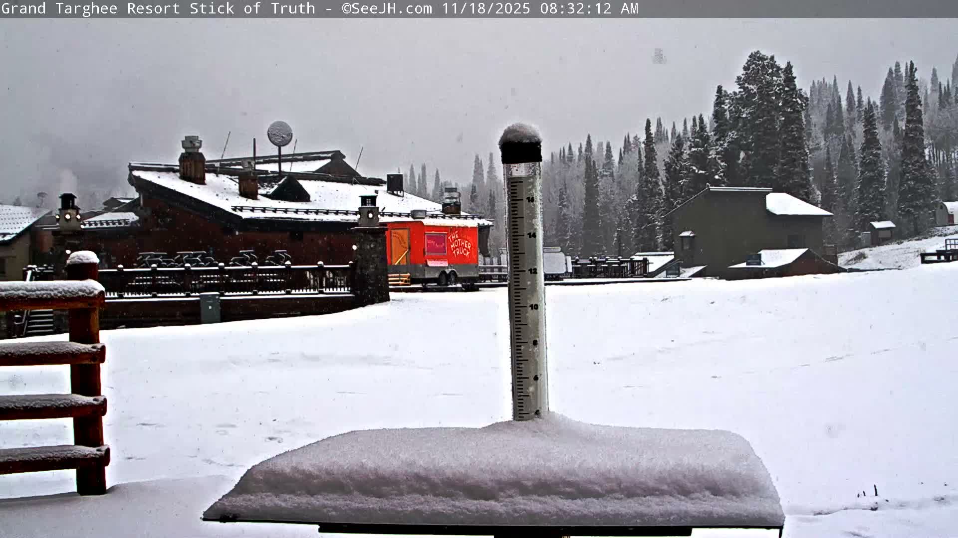 On a dark and humid night, a brightly lit resort lodge with steam rising from a chimney is partially obscured by prominent moisture streaks on the camera lens.