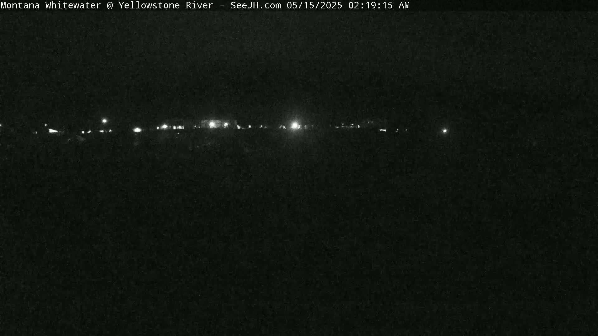 A dark, nighttime scene shows a line of distant lights on the horizon.