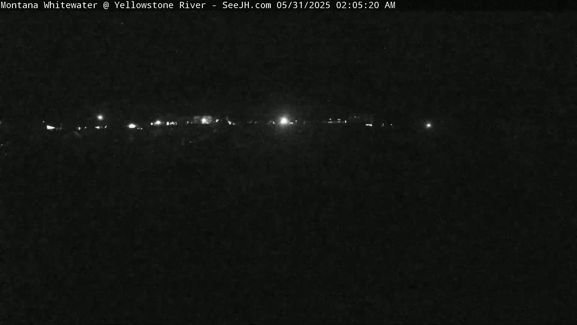A nighttime, low-light view of a distant line of lights at what seems to be a low-lying area.