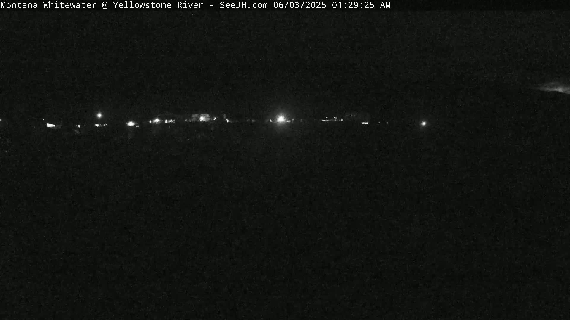A nighttime, low-light view shows a distant line of lights possibly indicating a road or buildings.