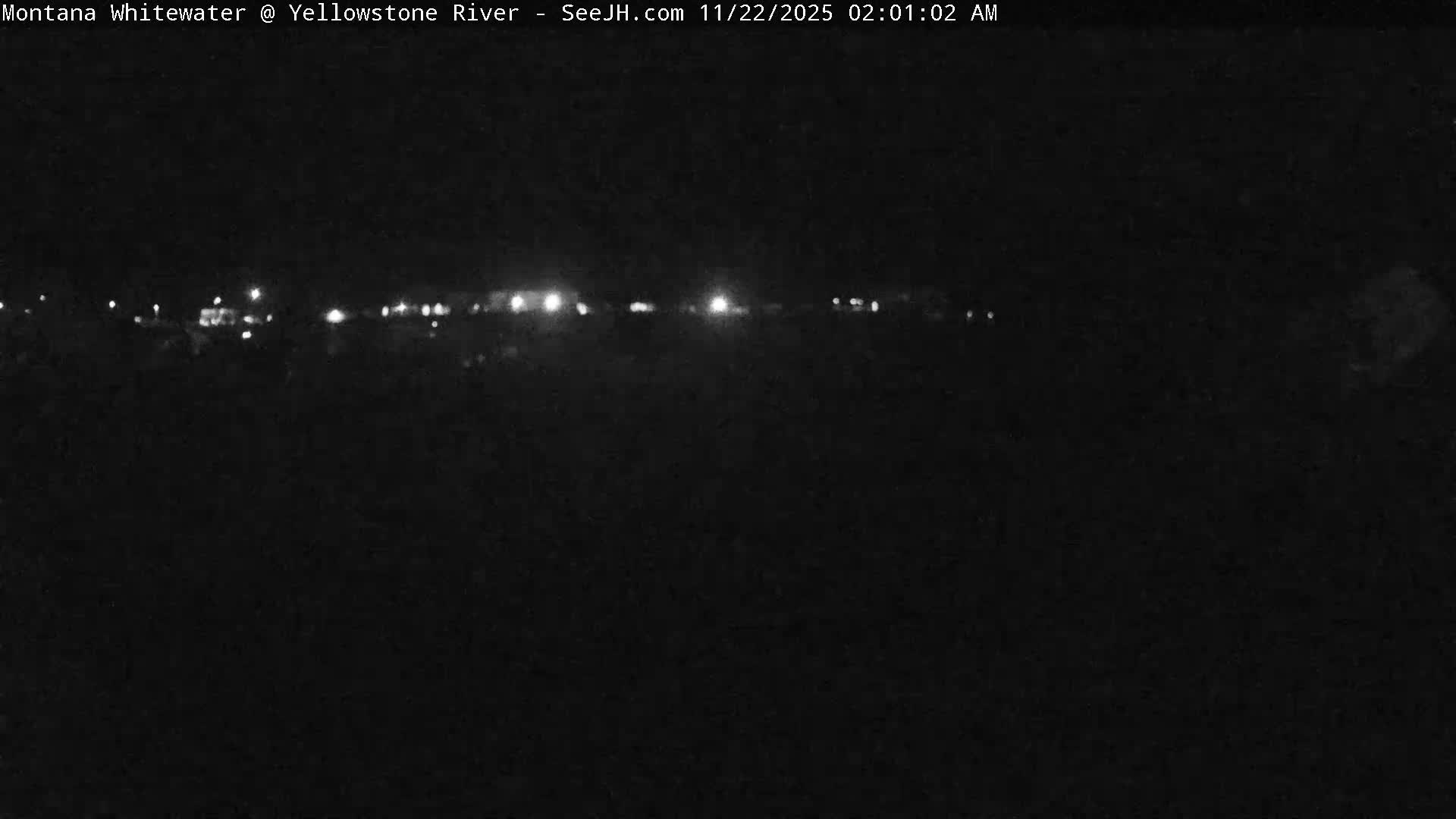 The image displays a very dark night scene with a horizontal line of scattered bright lights across the middle, suggesting a distant road or settlement.