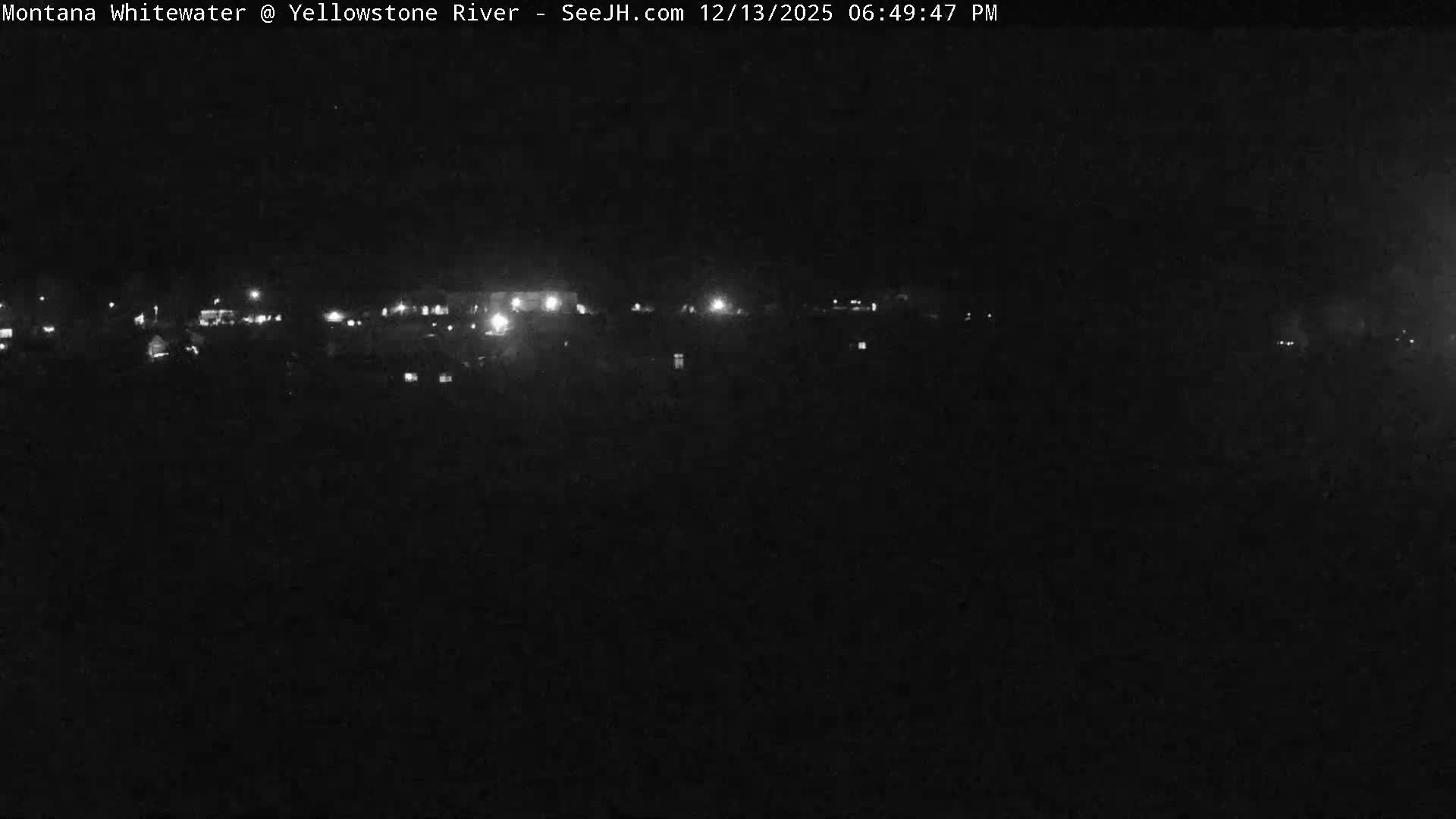 The image captures a dark night scene with numerous scattered lights illuminating a distant area, under clear weather conditions.