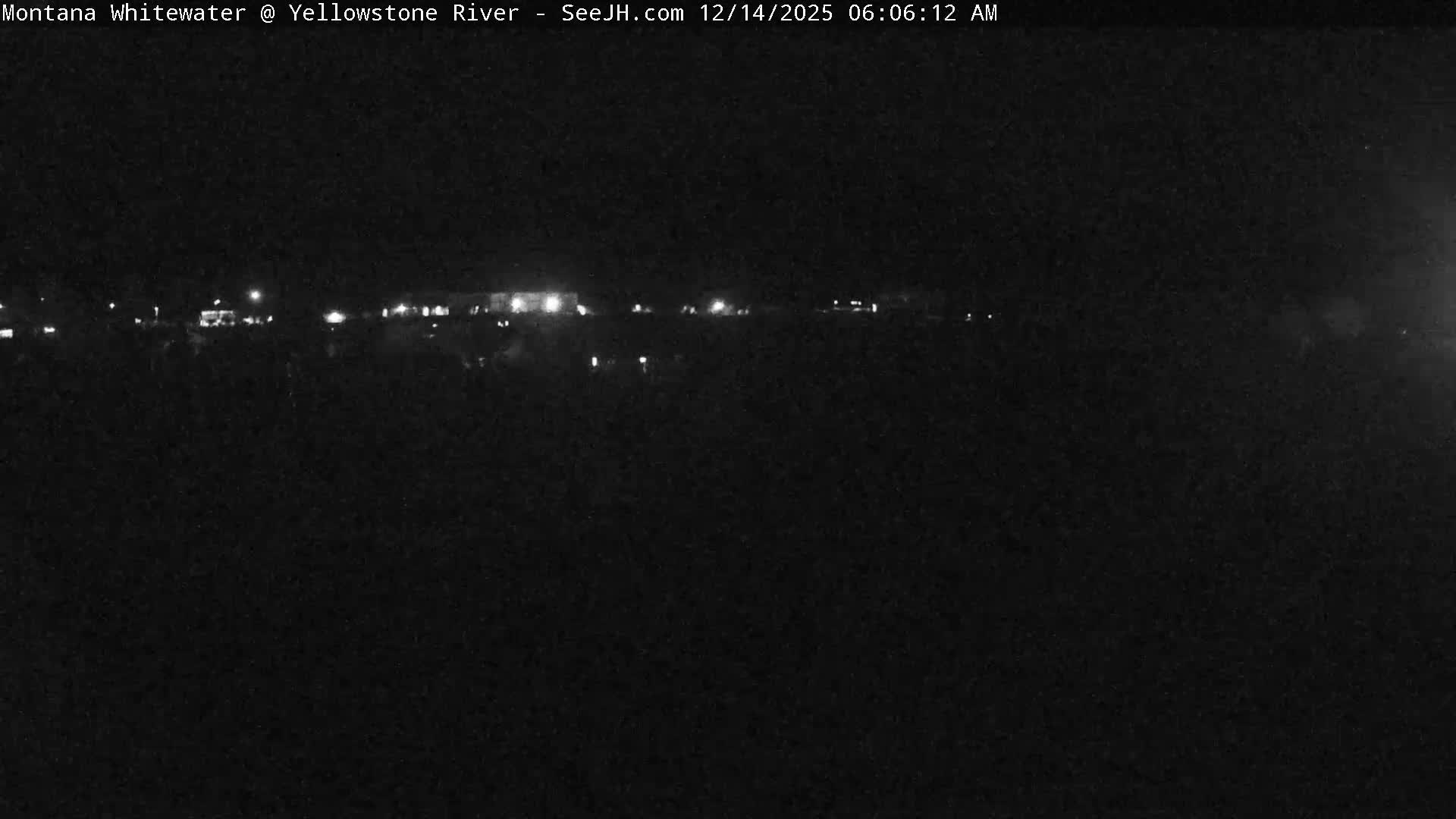 The image captures a dark night scene with numerous scattered lights illuminating a distant area, under clear weather conditions.